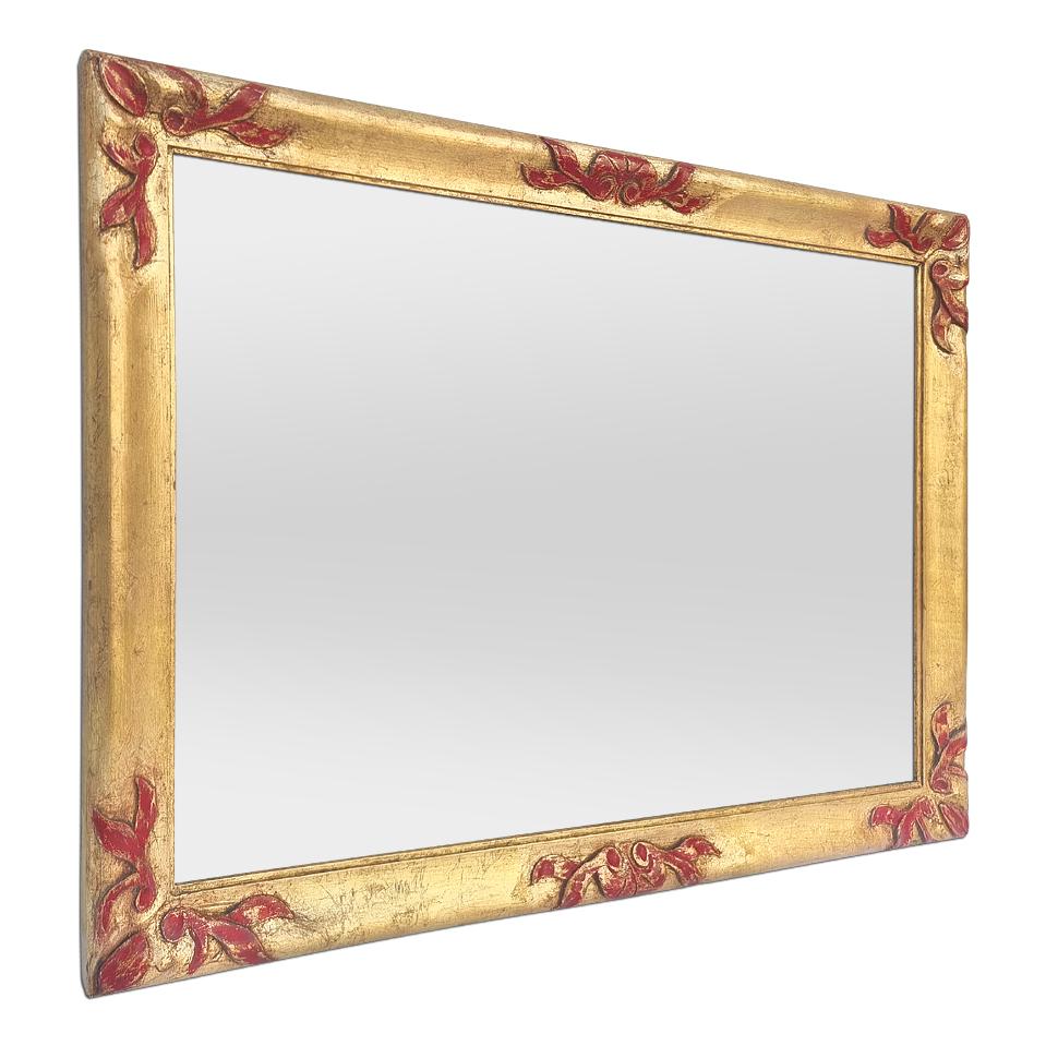 Antique gilded wood wall mirror from the 30's, decorated with stylized foliages in carved wood with a red colors patinated, circa 1930. Antique frame re-gilding to the leaf, orned with bas-relief polychrome carved wood of red colors. (Antique frame