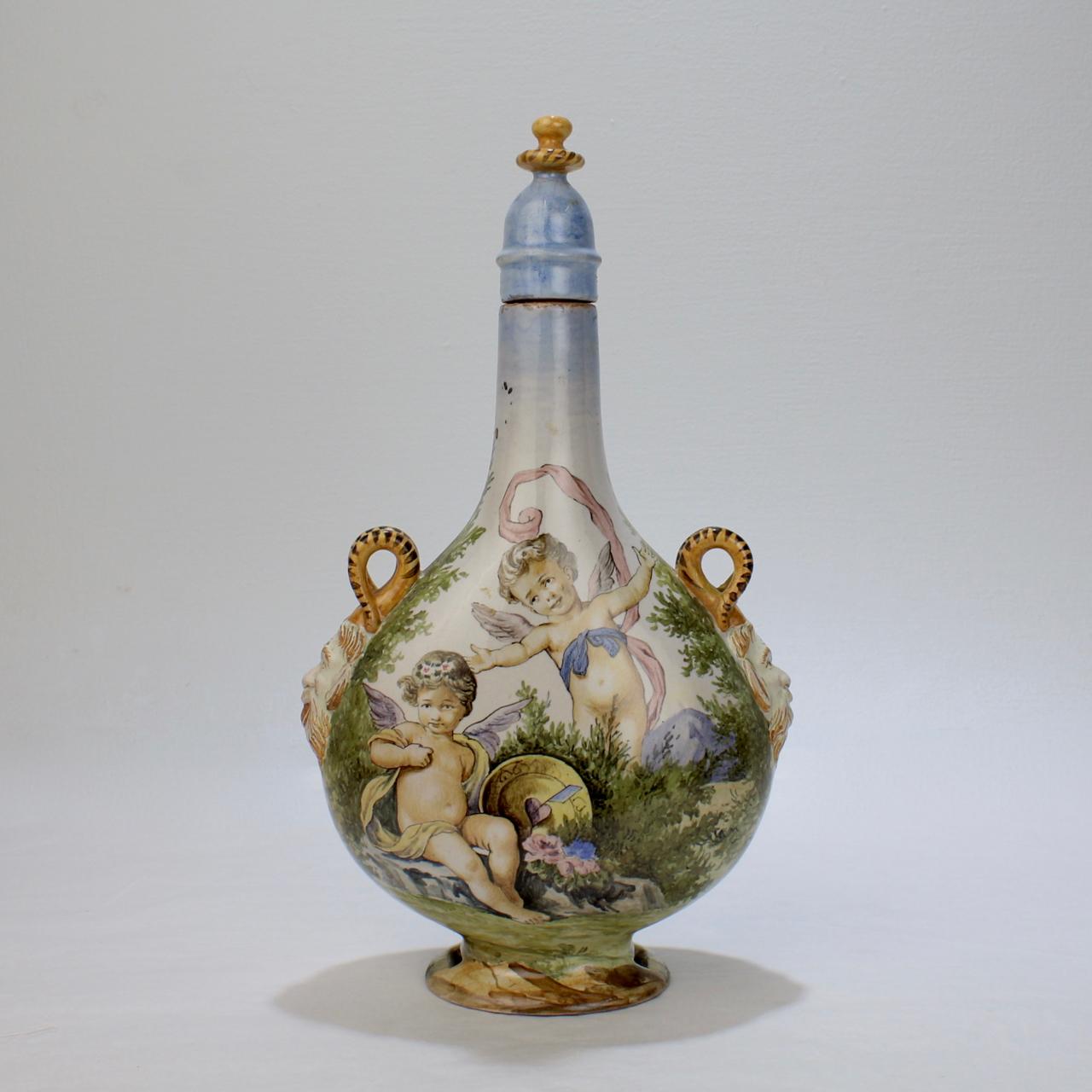 A very fine antique Maiolica pilgrim flask & stopper by Ginori.

Decorated in the Urbino istoriato style with polychrome cherubs to the front and a landscape scene to the reverse.

Having satyr form hands and a conforming cover. 

A fine form