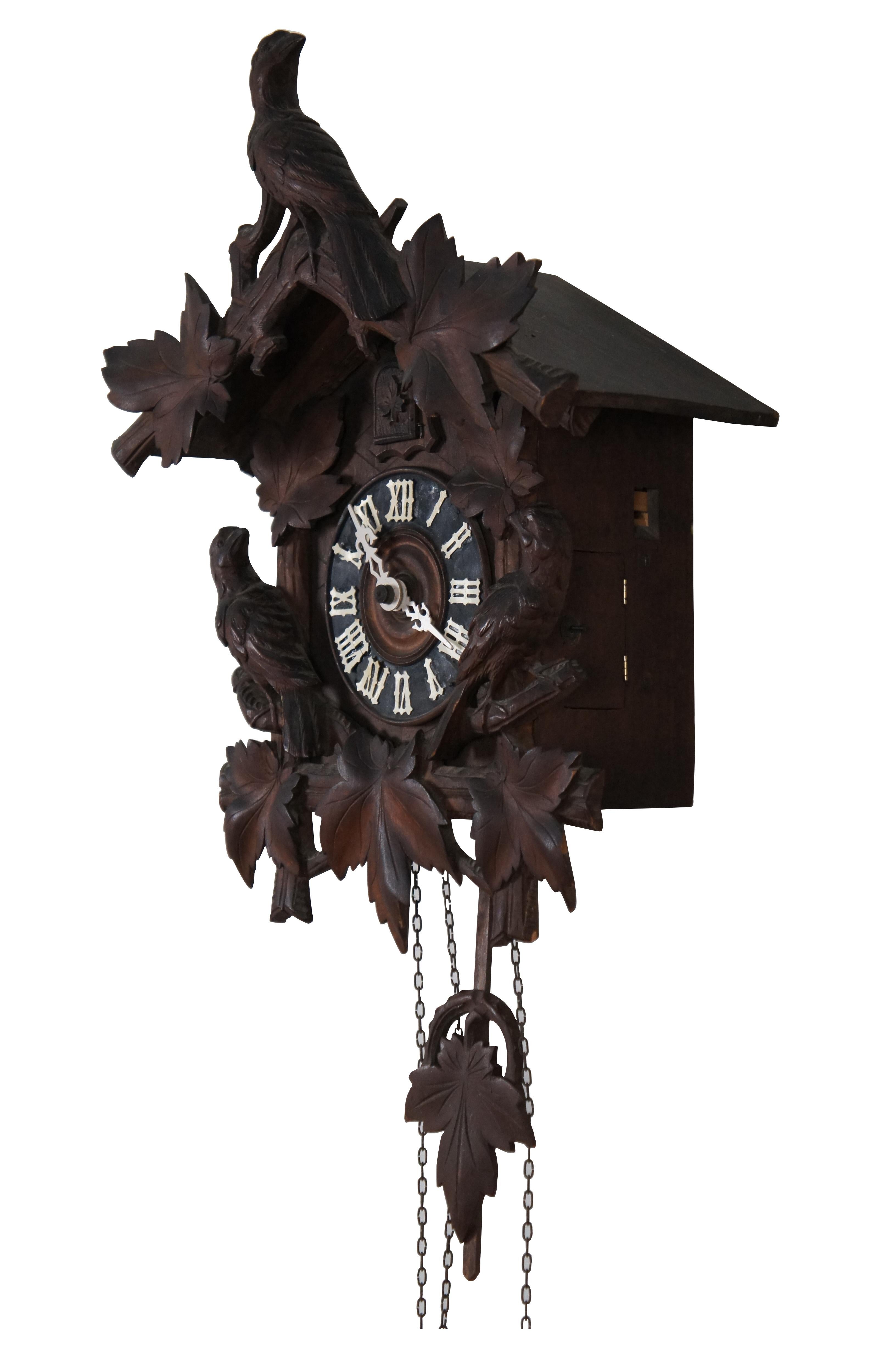 George Kuehl & Co. antique Black Forest carved wood cuckoo clock in the traditional house form, decorated with leaves and birds.  Includes pine cone shaped weights and additional pendulum. works marked G.K.  George Kuehl & Co., operated out of