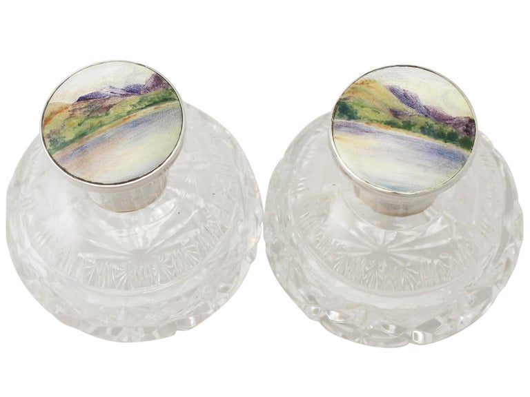A fine and impressive pair of antique George V English sterling silver, glass and enamel scent bottles; an addition to our silver mounted glass collection.

This fine pair of antique George V glass scent bottles has a circular rounded form.

Each
