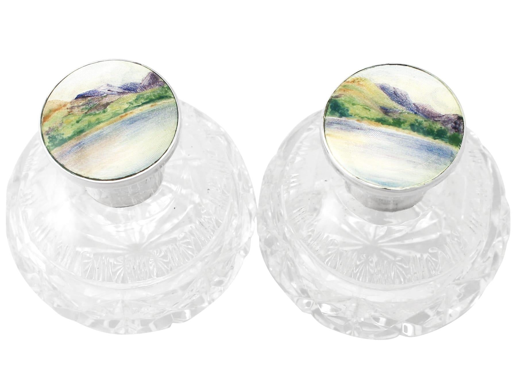 A fine and impressive pair of antique George V English sterling silver, glass and enamel scent bottles; an addition to our silver mounted glass collection.

This fine pair of antique George V glass scent bottles has a circular rounded