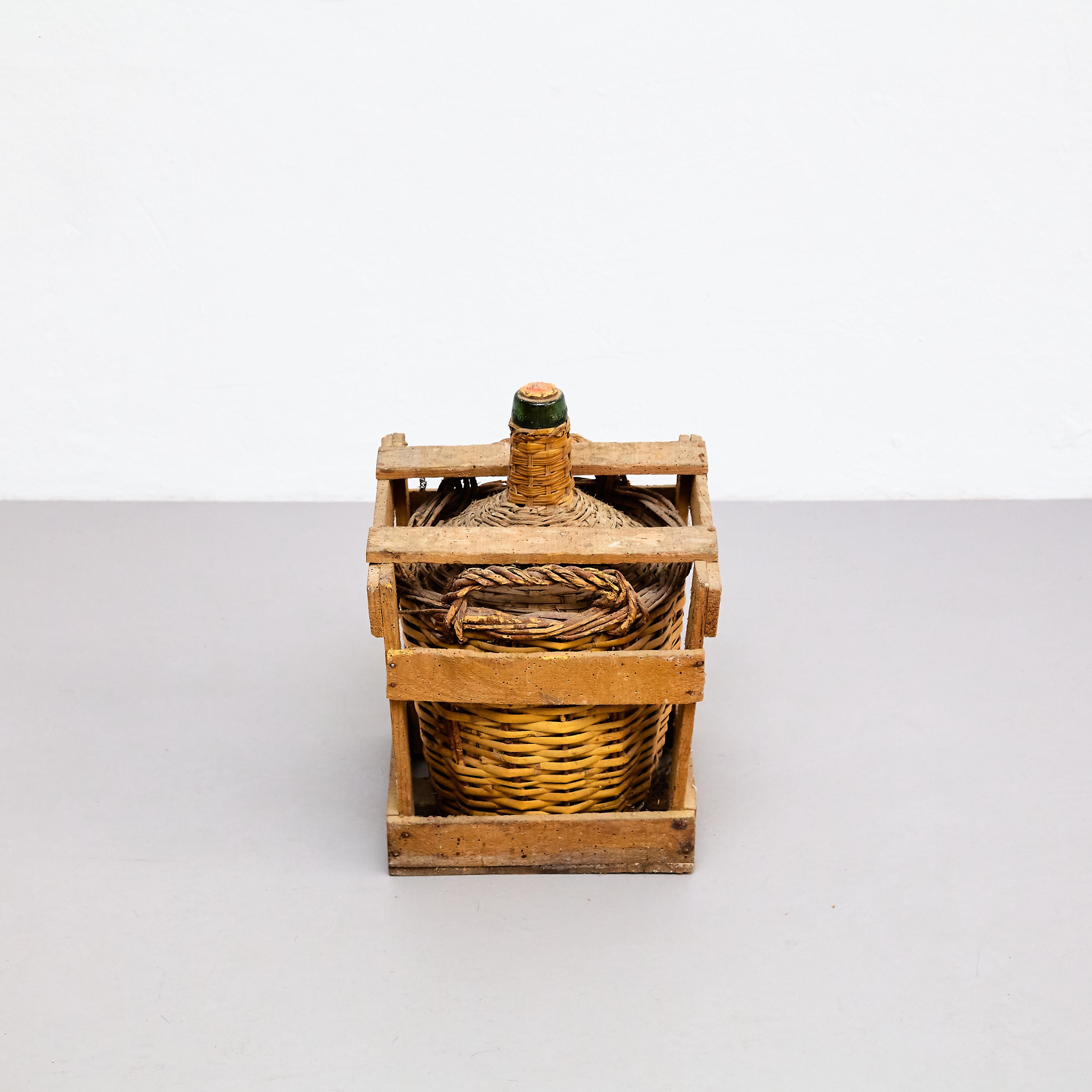 Antique Damajuana glass bottle with rattan and wood basket, by unknown artist.

Manufactured in Barcelona, circa 1950.

Materials:
Glass, rattan, wood.

Dimensions:
D 30 W 31.8 H 41.5

In original condition, with some visible signs of