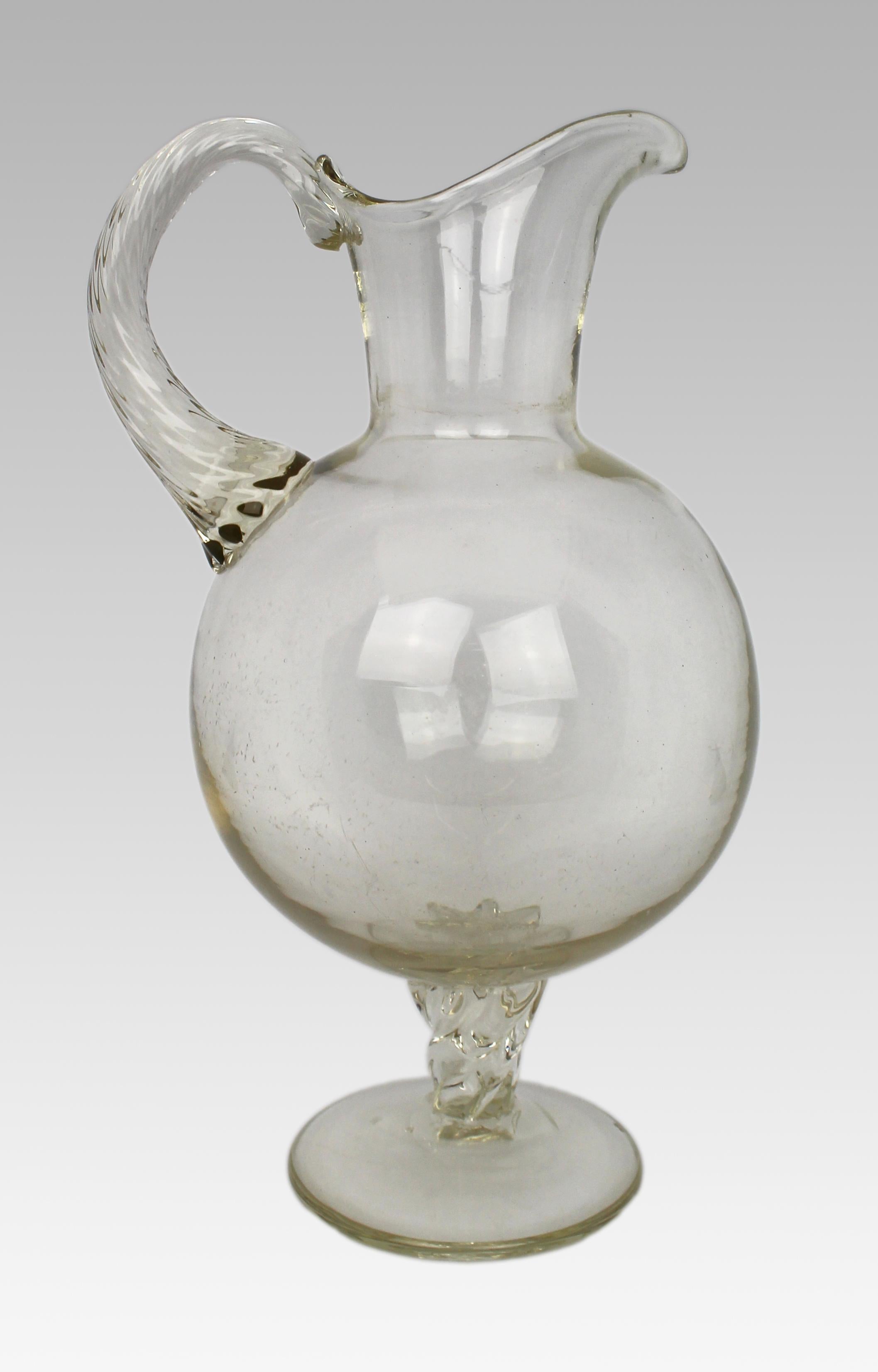 Antique Glass Footed Ewer, Late 19th Century

This antique footed ewer, dating from the late 19th century (around 1880-1900), features a globular body with a twisted handle and matching twisted pedestal. The glass has a subtle yellow tint,