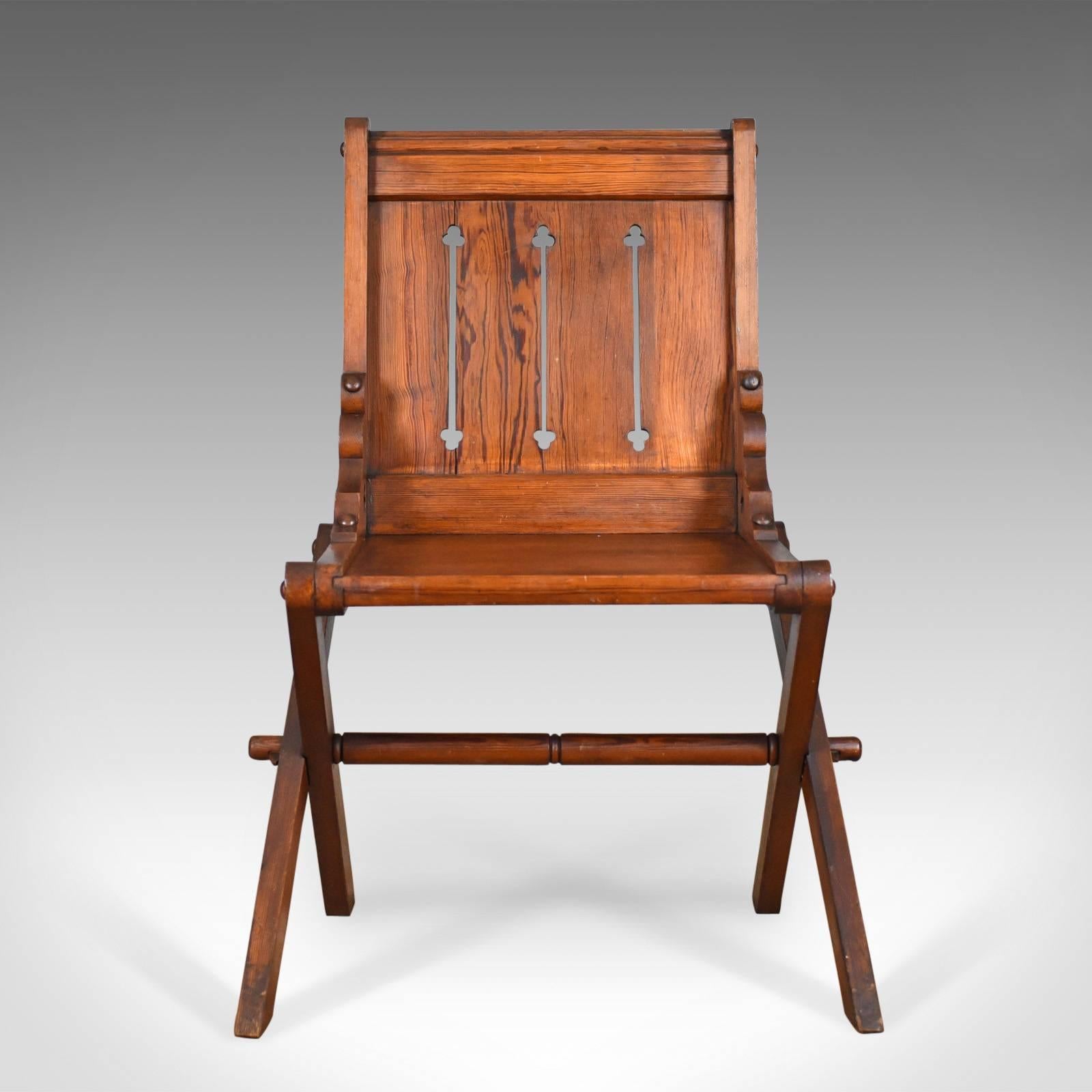 This is an antique Glastonbury chair, English Tudor Revival carved hall seat dating to the late 19th century, circa 1880.

An unusual, arm-less Glastonbury chair in pitch pine
Exhibiting ecclesiastical and gothic overtones
Classic tusked joints