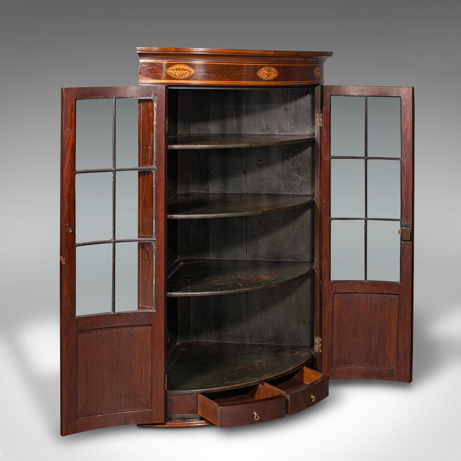 This is an antique glazed corner cabinet. An English, mahogany and glass bow front display cupboard, dating to the Georgian period, circa 1800.

Striking cabinetry with delightful glazing and inlaid detail
Displaying a desirable aged patina and in