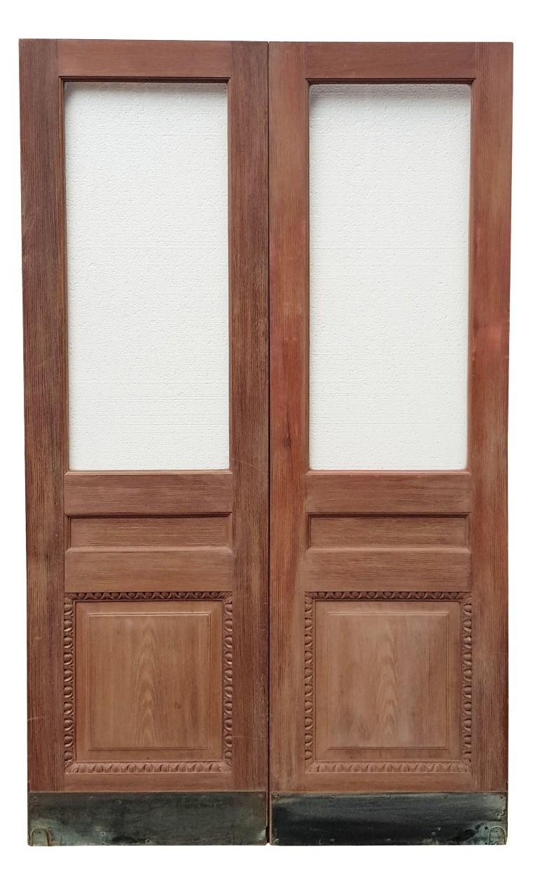 These impressive teak doors have raised and fielded panels, with ‘Egg and Dart’ carved mouldings. The original clear glass is present and undamaged. The doors have been stripped, feature a brass kick plate and there is no handle present. The doors