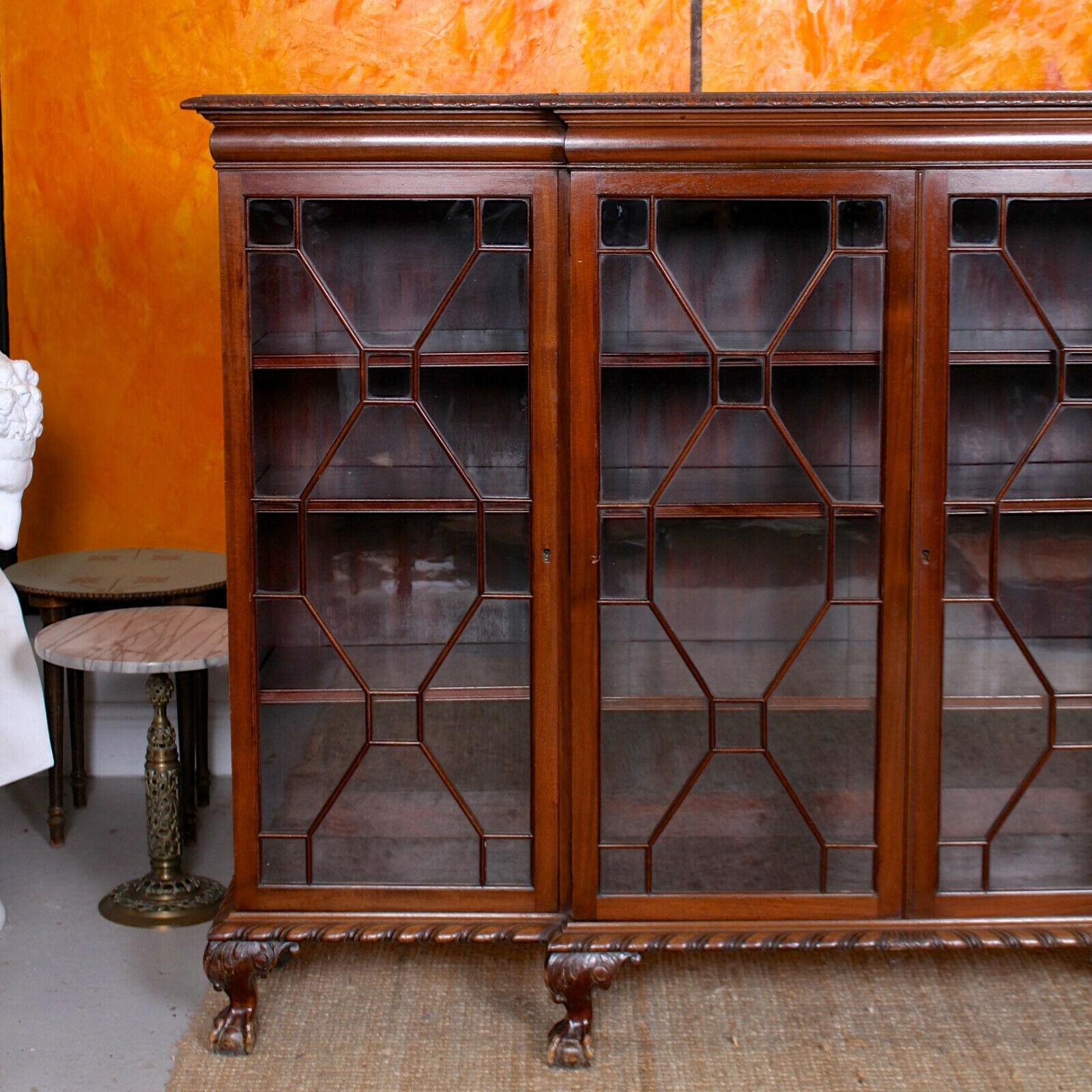 An impressive Edwardian period breakfront astragal glazed bookcase.

The breakfront top with acanthus carved edges above four astragal glazed doors enclosed mahogany shelving and raised on a matched acanthus carved apron and claw and ball