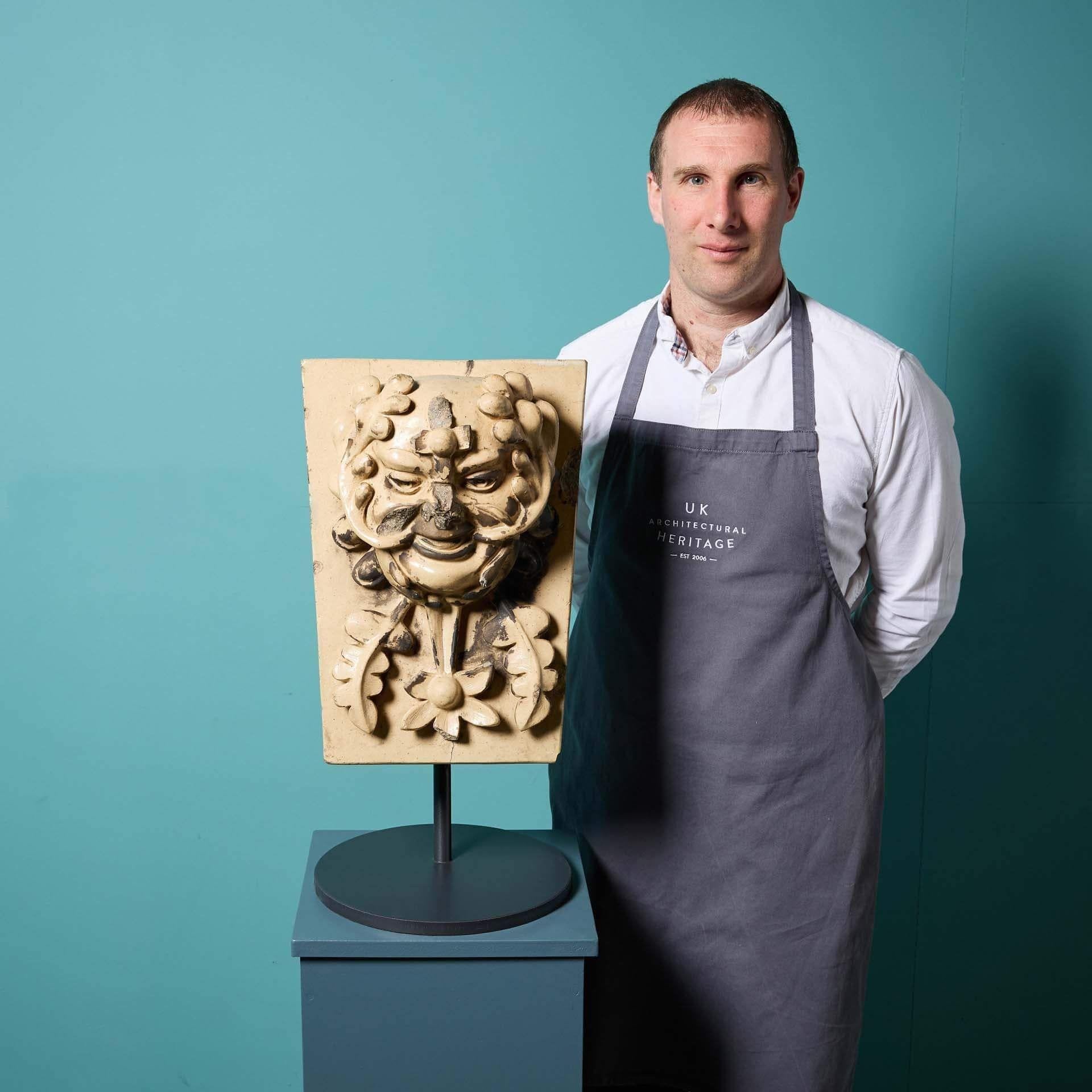 Un'antica chiave di volta in terracotta smaltata di Lipscombe & Co. (stampata) raffigurante una maschera di Greene & Greene, recuperata da una casa privata britannica e montata su un supporto in acciaio su misura per essere esposta all'interno.