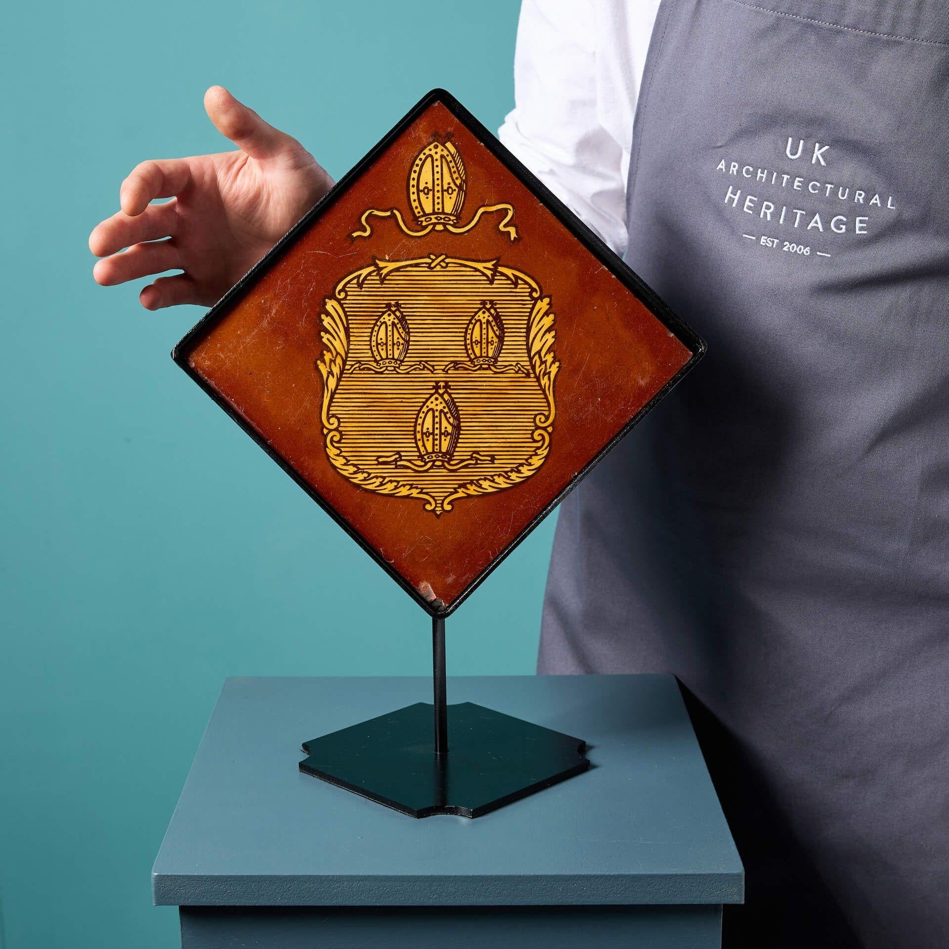 An antique glazed terracotta tile by Campbell Tile Co, Stoke on Trent.

Dating to circa 1880, this 8-inch terracotta tile is decorated with heraldic motifs of a bishop’s mitre in buff terracotta on a rich background.

Mounted on a bespoke steel