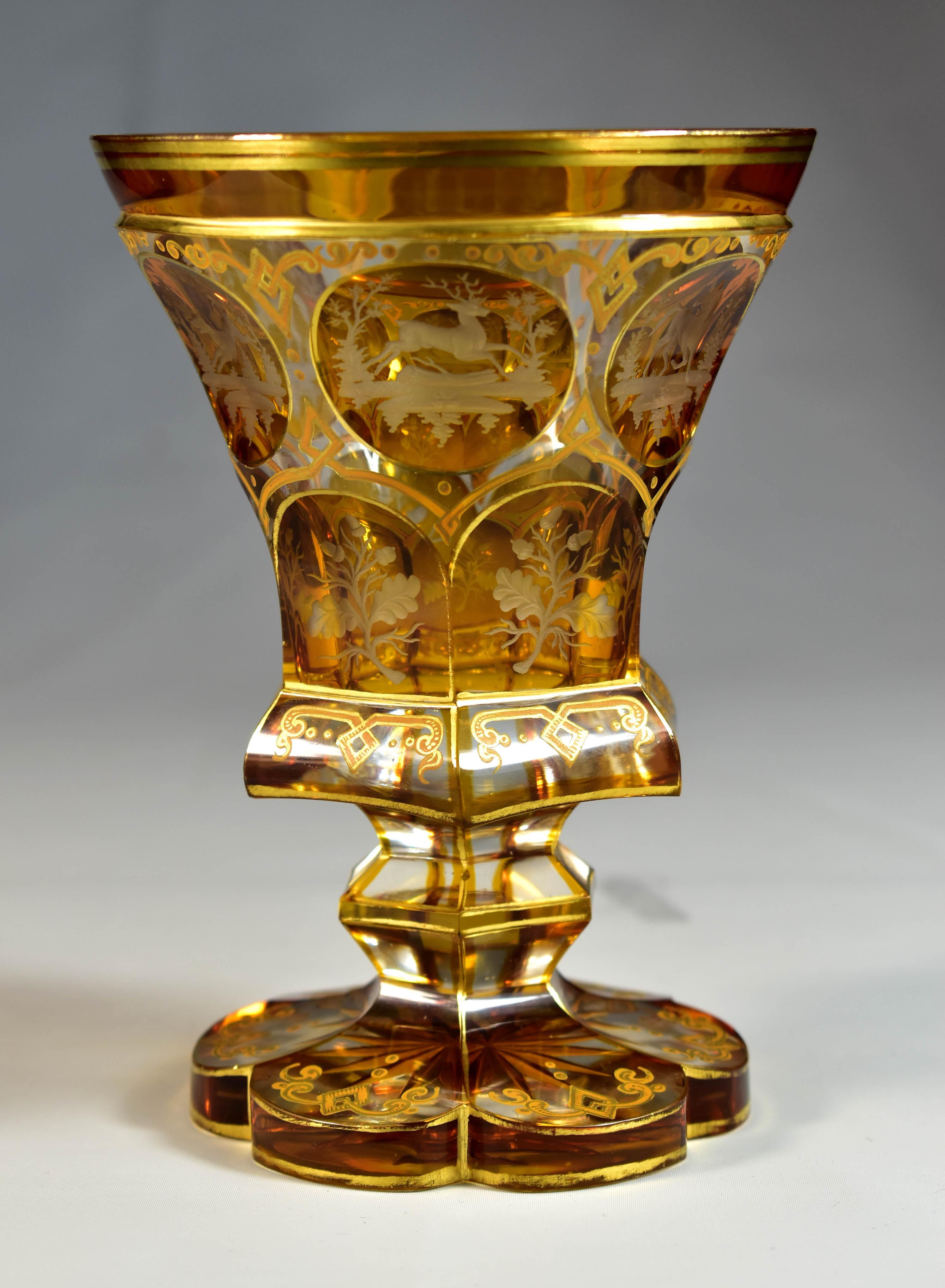 Beautifully cut clear goblet with amber glaze. There are six medallions with miniature engravings of animals. Below the medallion are also six portals where there are engravings of oak leaves with acorns. Everything is complemented by an ornamental