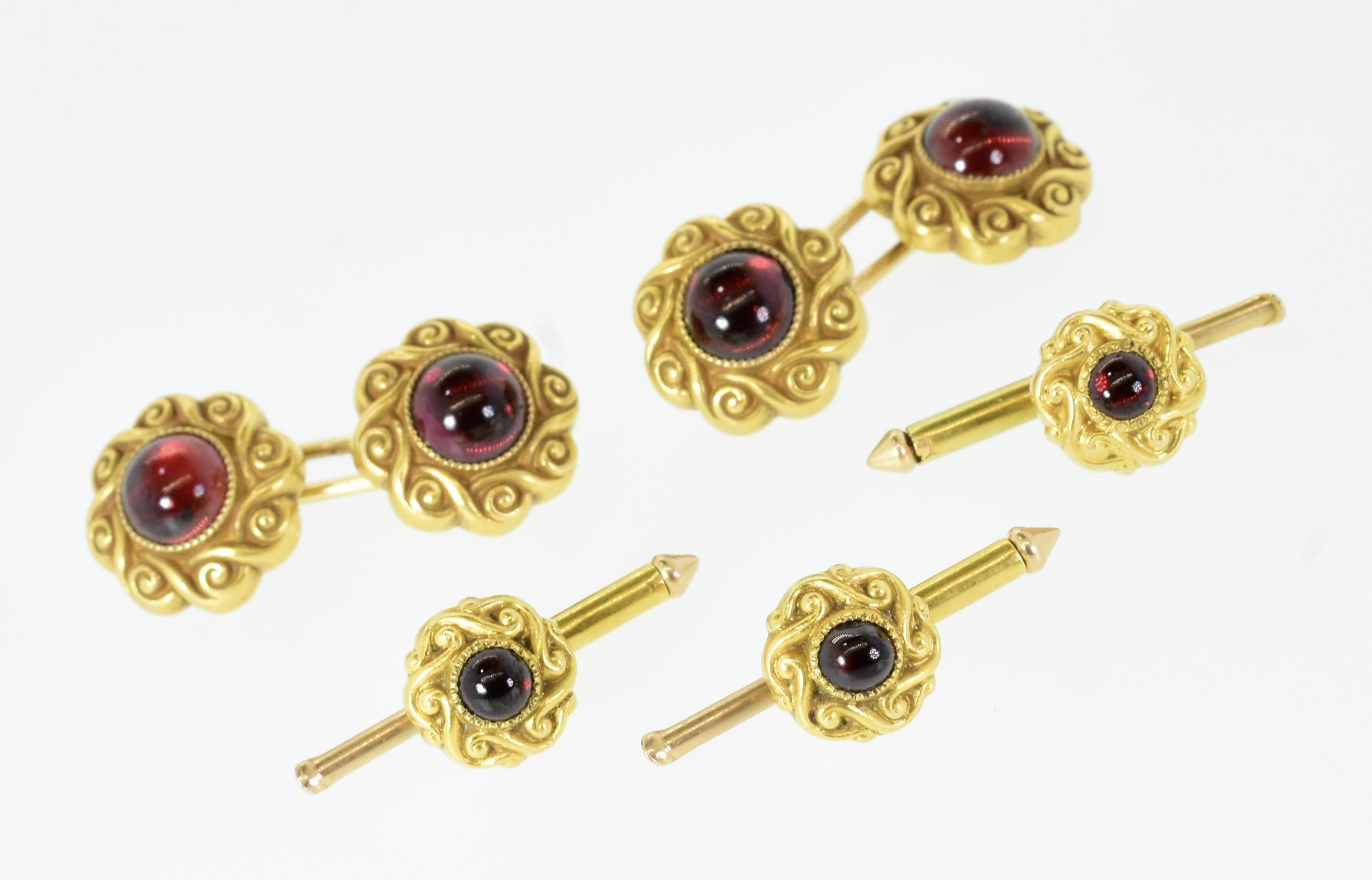 Victorian cuff and stud set.  Bright red garnets are cut en cabochon and set within a finely mil-grained bezel. The bright yellow gold rims are hand engraved in a scroll like motif.  The cufflinks measure 12.11 mm. in diameter, the studs measure 8.3