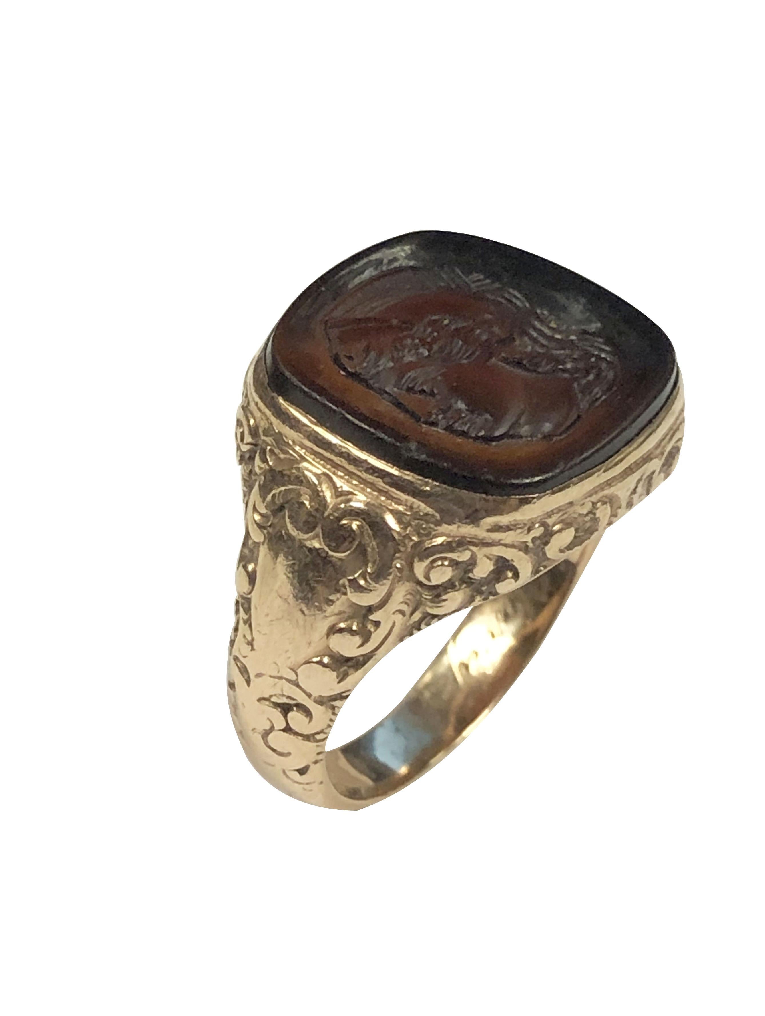 Circa 1910 14k Yellow Gold Intaglio Signet Ring, the top measures 9/16 X  9/16 inch and is set with a dark Red Ancient Greek - Roman style Intaglio. Hand chased design work on the sides of the Ring and an engraved presentation in the ring shank that