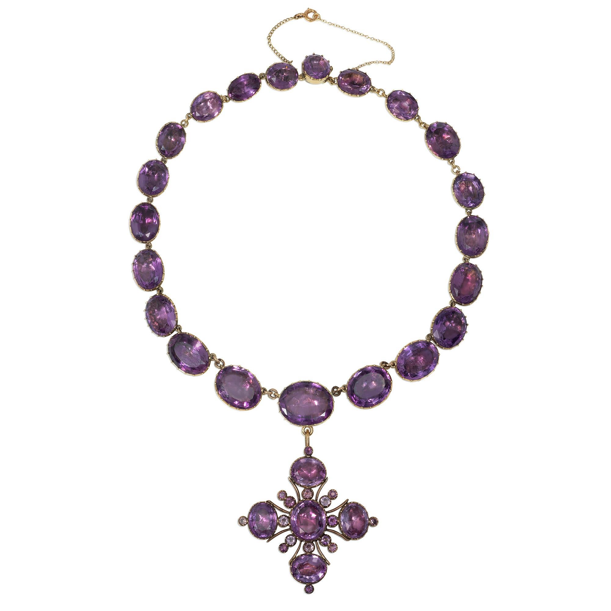 Un'antica collana rivière di ametista di epoca georgiana, composta da ametiste ovali graduate con supporto in lamina, che sospende un ciondolo a croce maltese staccabile in oro e ametista, in 14 carati.

Dimensioni: collana lunga 15