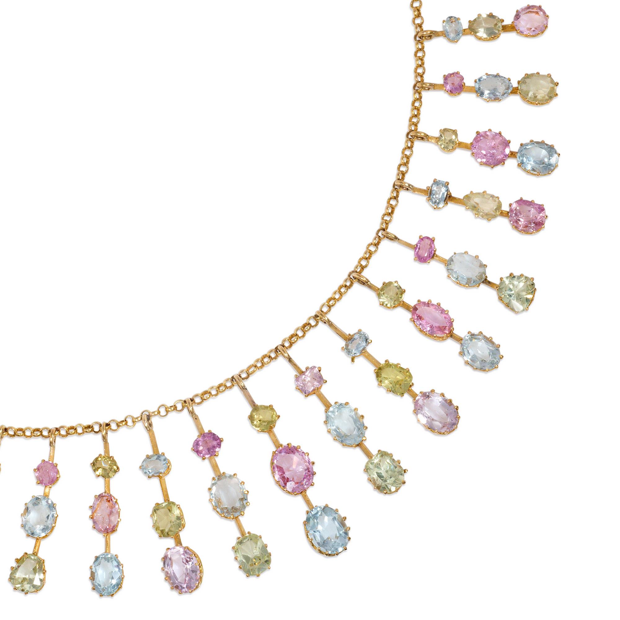 An antique Victorian period gold and multi-gem necklace of fringe design, comprised of graduated knife-wire pendants set with aquamarines, pink topaz, and chrysoberyls, in 15k gold.  England

Dimensions: 15 3/4