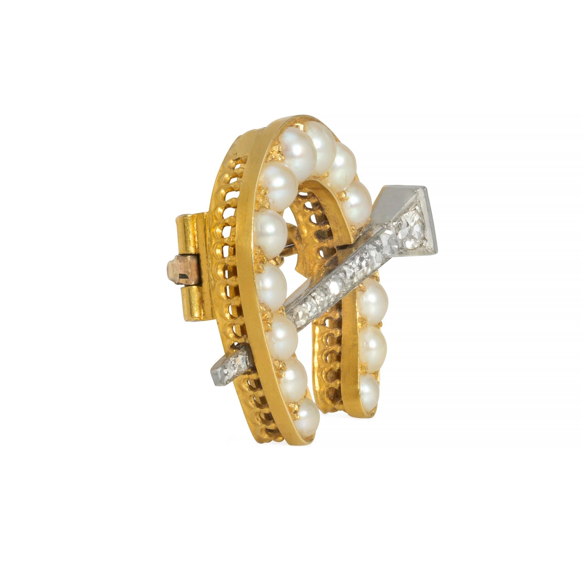 Edwardianische Brosche in Form eines mit Perlen besetzten Hufeisens, durchbrochen von einer Pavé-Diamantnadel, mit Anhängerschlaufe, aus 18 Karat Gold und Platin. 