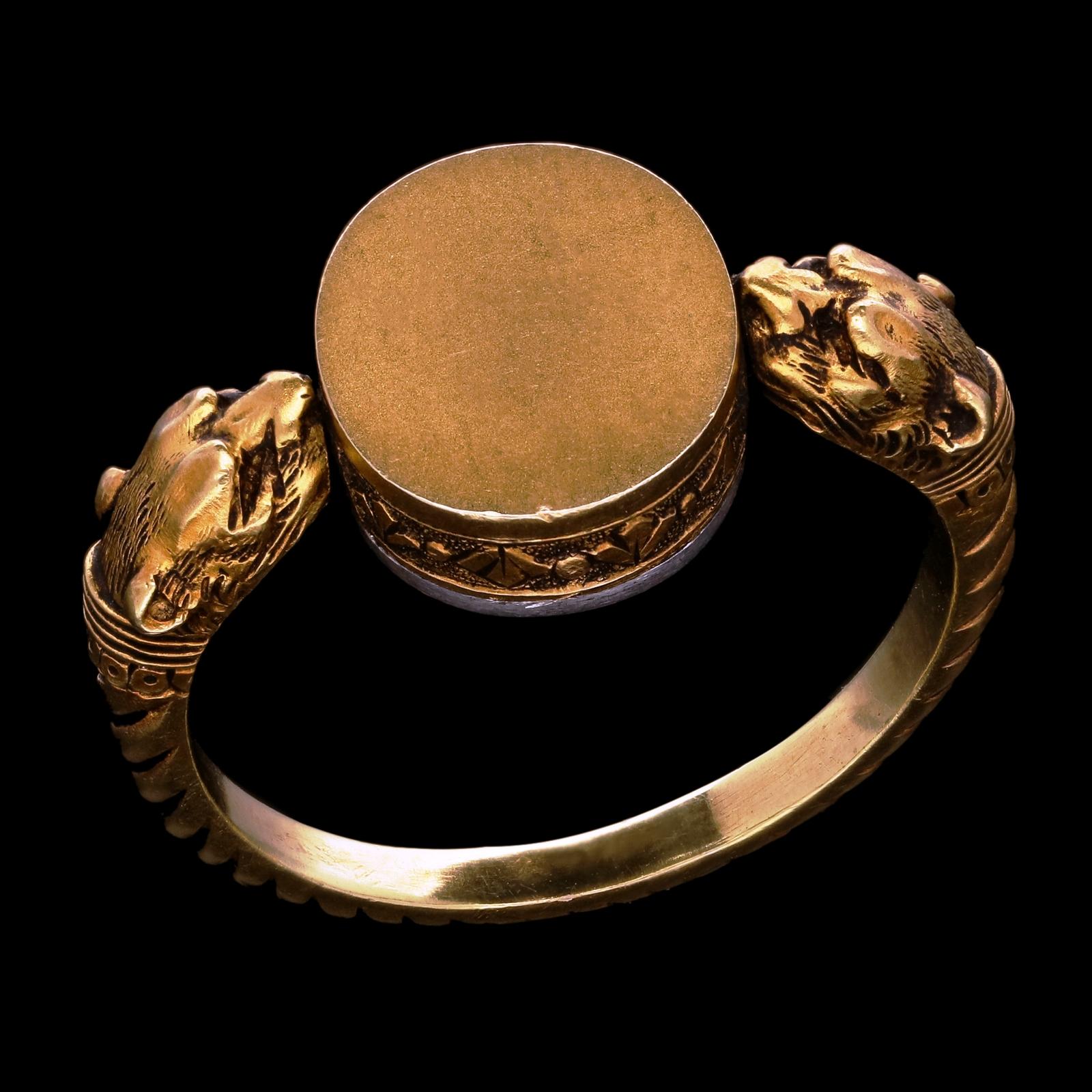 An unusual antique French gold double lion head swivel signet ring c.1880, the rope twist band terminating either side in a lion’s head between which is an oval two tone plaque with stylised fleur-de-lys motifs around the edge which swivels round,