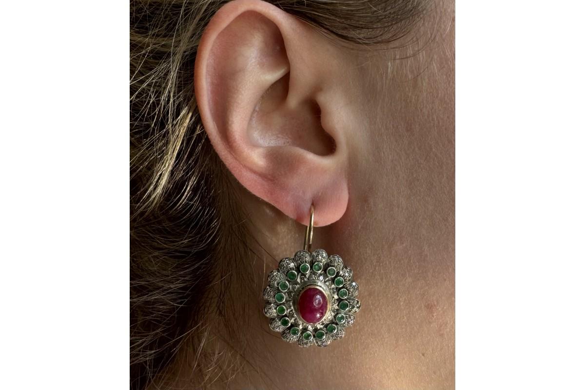 Pendientes de oro viejo decorados centralmente con rubíes talla cabujón de un peso aproximado de 7,00 ct. Además, los pendientes están decorados con 32 esmeraldas de 2,00 ct y 224 diamantes de 1,20 ct.

Pendientes de 580 elementos de oro y