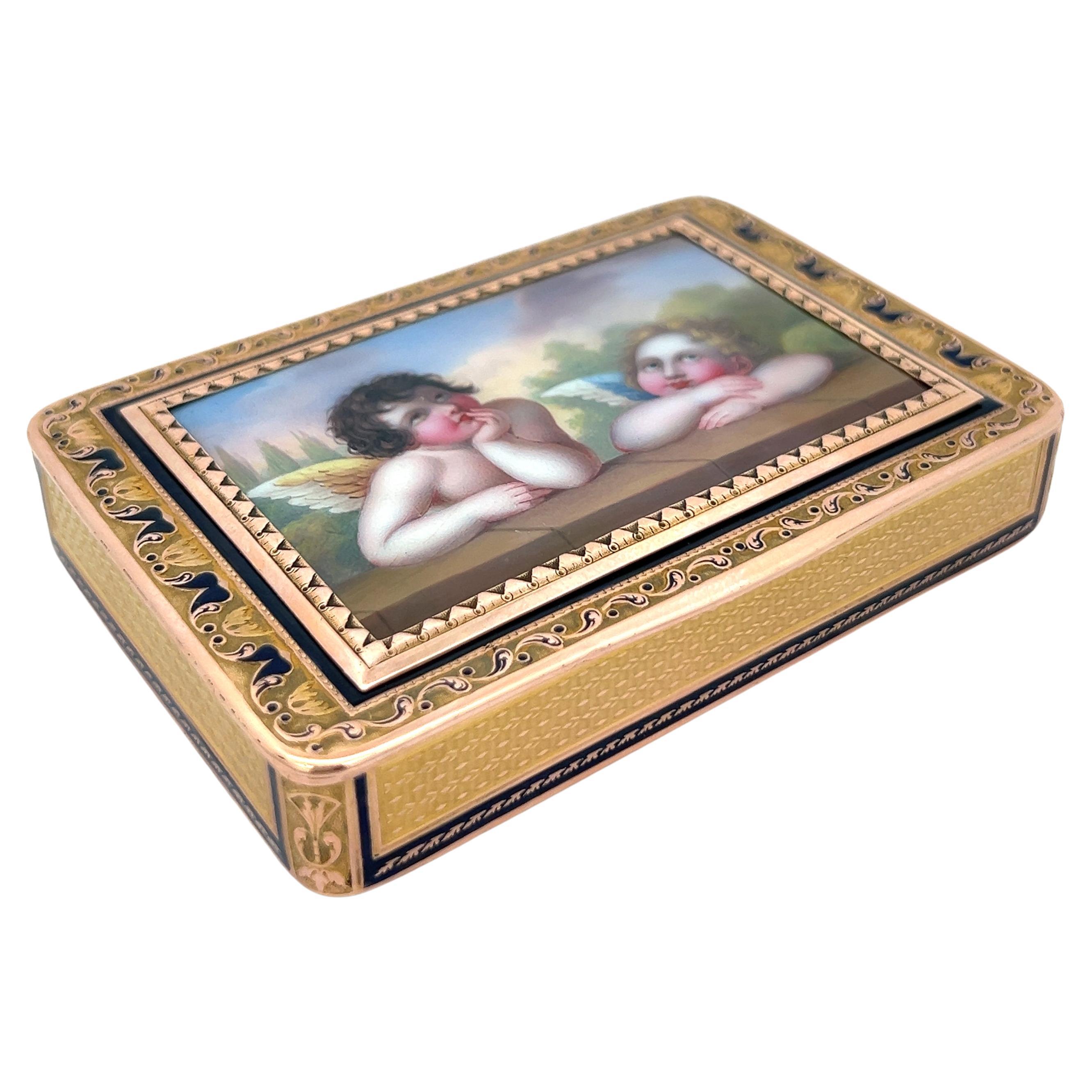Antique Gold & Enamel Cupid Motif Snuff Box 

Made circa 1815.

A gold snuff box featuring a rectangular lid consisting of an enamel plaque adorned with depictions of two putto accented with a fine gold zig-zag border and a black enamel frame.