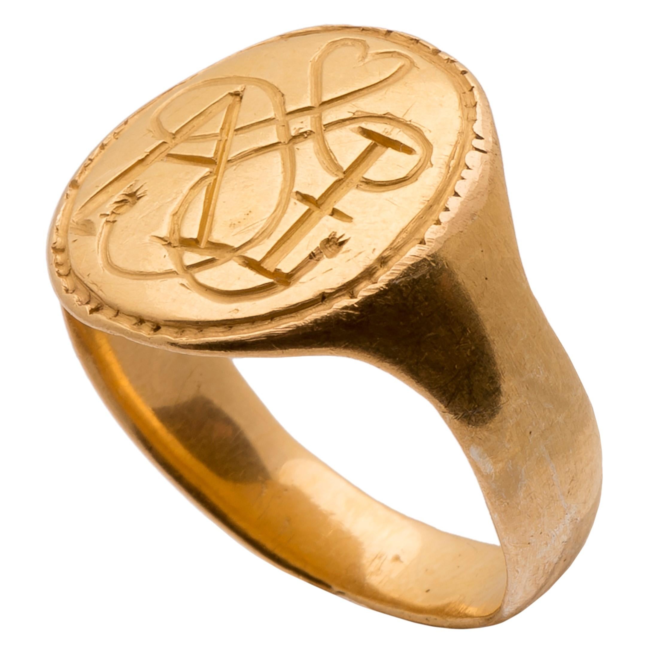 Signet Ring with True Lover’s Knot and the Initials “AI”
England, 17th century 
Gold
Weight 9 gr.; bezel 15.3 x 16.1 x 1.5 mm.; circumference: 58.21 mm.; US size 8.5; UK size Q ¾

The wide gold hoop is plain, flat inside and slightly rounded on the