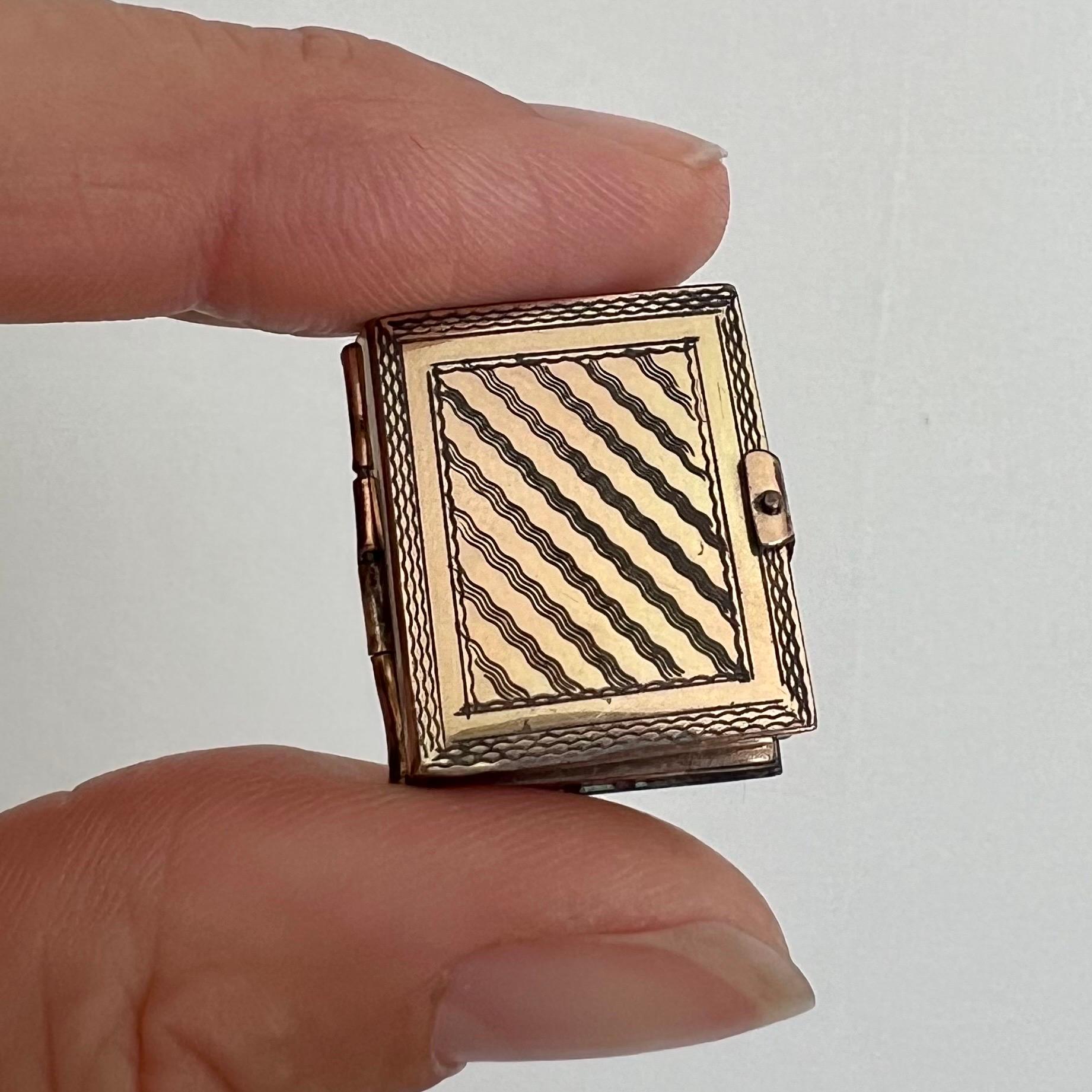 This Antique Gold Family Book Locket Pendant is a charming and sentimental piece of jewelry, designed to hold the memories of loved ones close. Crafted from 9 karat gold, the pendant is shaped like a miniature book, with intricate engravings on both