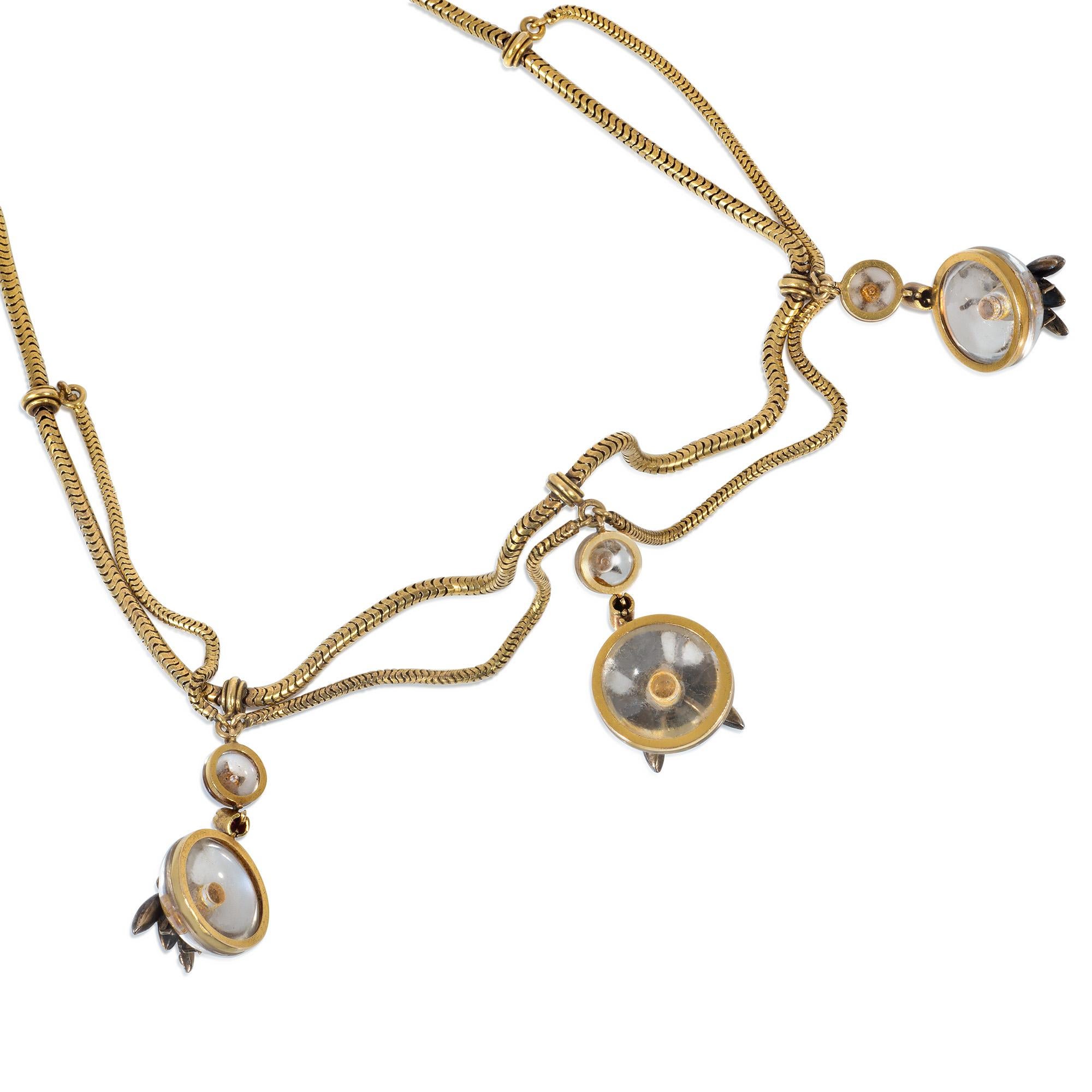 An antique Victorian period gold, rock crystal, and multi-gemstone festoon necklace comprising swags of gold snake chain suspending carved rock crystal pendants set with ruby, emerald, diamond insects with star-set surmounts, in 15k. 