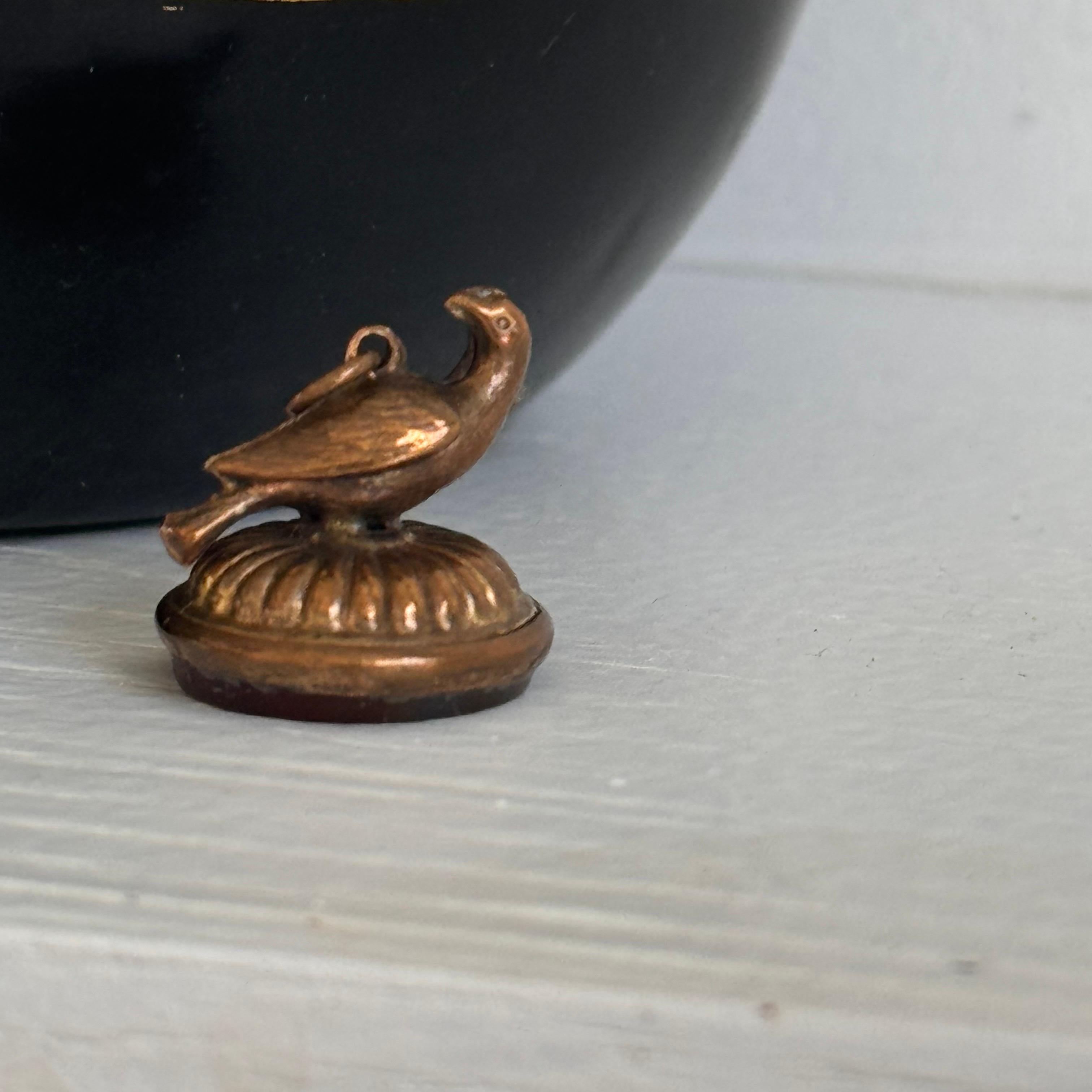 Questo affascinante ciondolo a forma di orologio vittoriano combina una raffinata lavorazione artigianale con un design unico. Il ciondolo è realizzato in metallo riempito d'oro e presenta uno squisito uccello in 3D appollaiato in cima a una pietra
