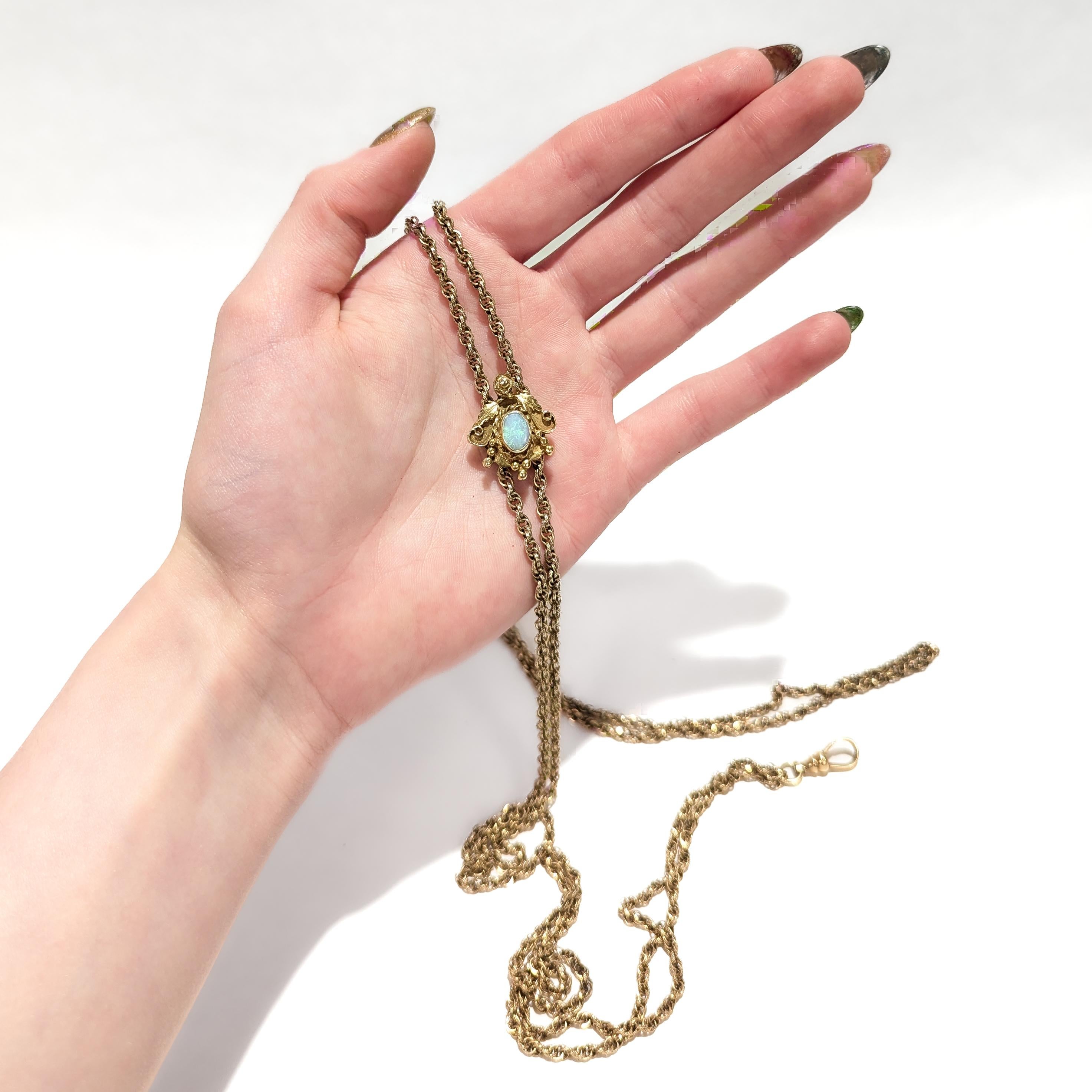 Una raffinata collana a catena longuard di epoca edoardiana.

La catenina e il fermaglio sono in oro; il cursore in oro giallo 14 carati.

Il vetrino presenta un cabochon di opale incastonato in una cornice di foglie d'oro, bacche e fiori. 

Fissato