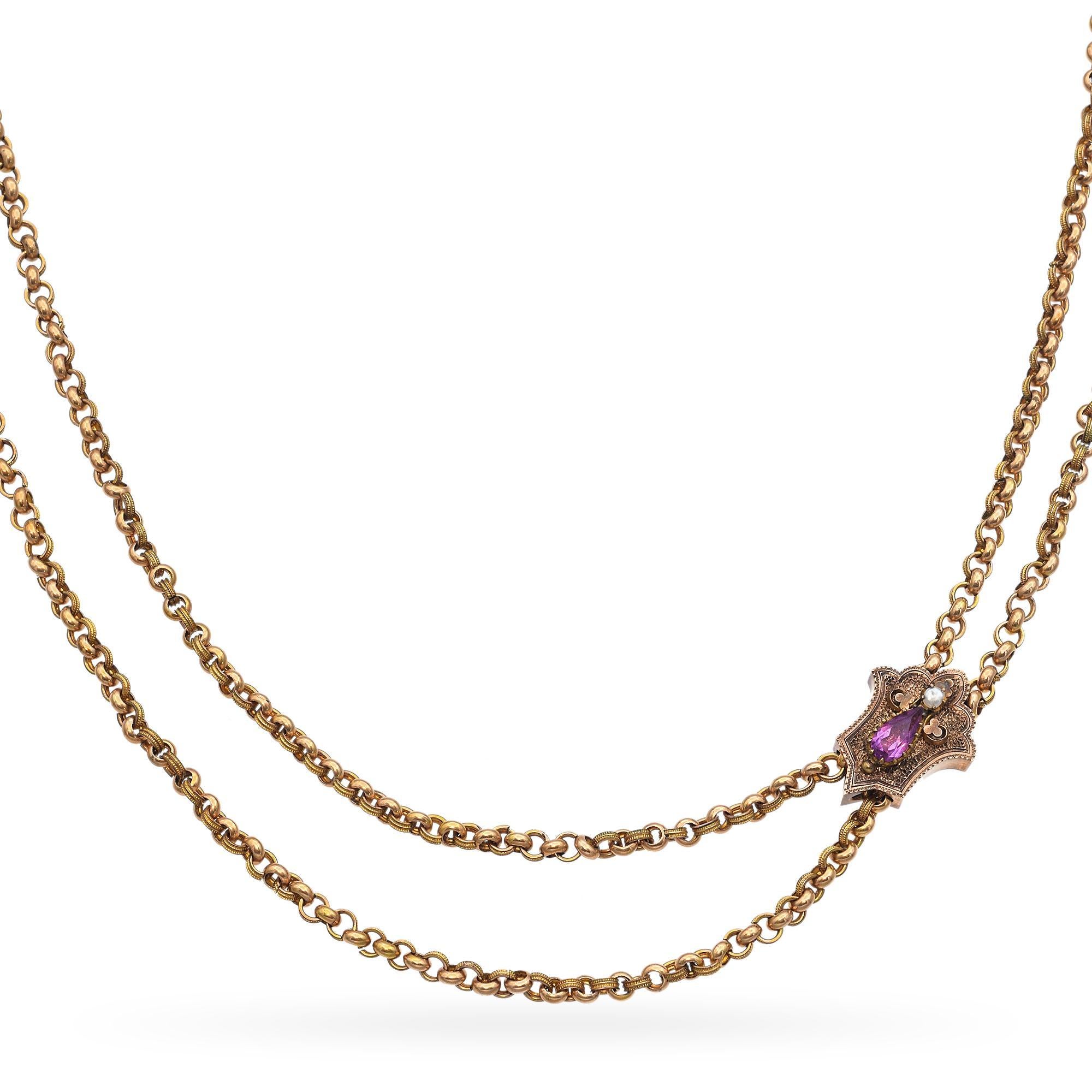This intricate necklace is crafted in gold-filled metal. The piece features a central pendant adorned with a pearl and a purple paste accent. The chain is composed of interlocking links, creating a fluid and elegant design. Clasp is 14k
