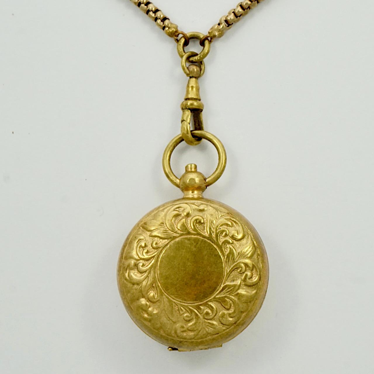 Antique gold gilt metal long guard chain with dog clip, and featuring an attached brass sovereign coin holder pendant. The dog clip would have originally been used to hold a pocket watch. The coin holder has decoration to the front and opens by