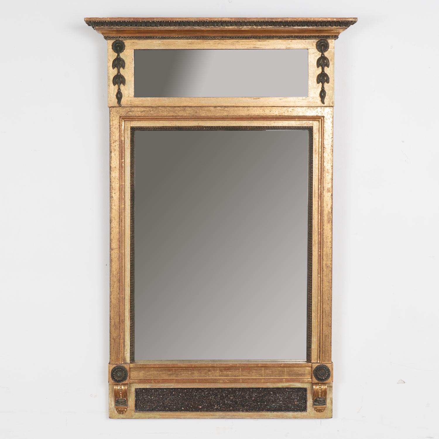 Lovely trumeau mirror with applied carved swags, flower medallions, and beaded trim. At 4' tall, it will provide a striking decorative presence. 
Restored, the gold and bronze gilt is accented with soft burnished red undertones and dramatic black