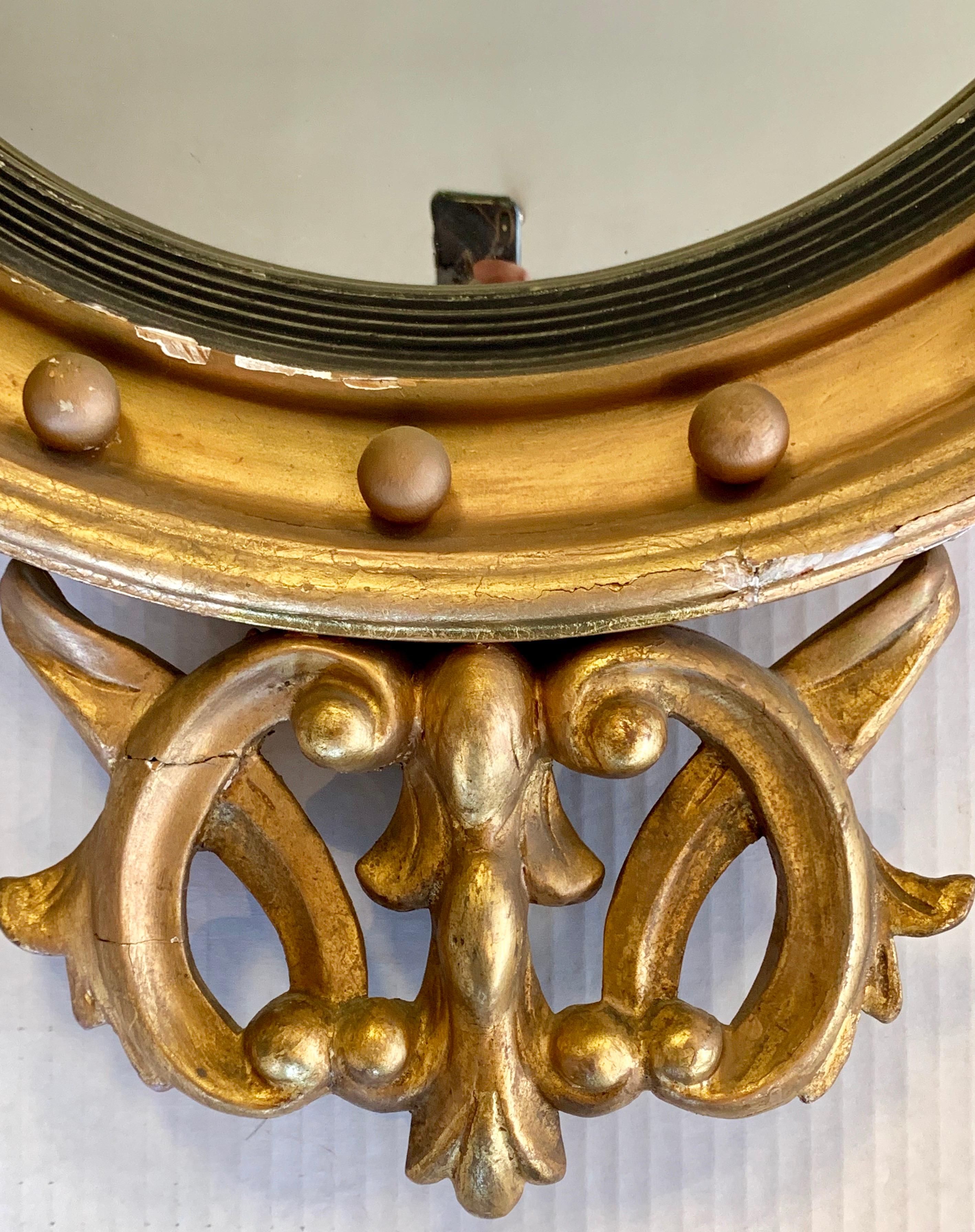 Stunning Regency style antique giltwood convex mirror with carved acanthus leaf and scrollwork with a winged dragon sitting on top.
