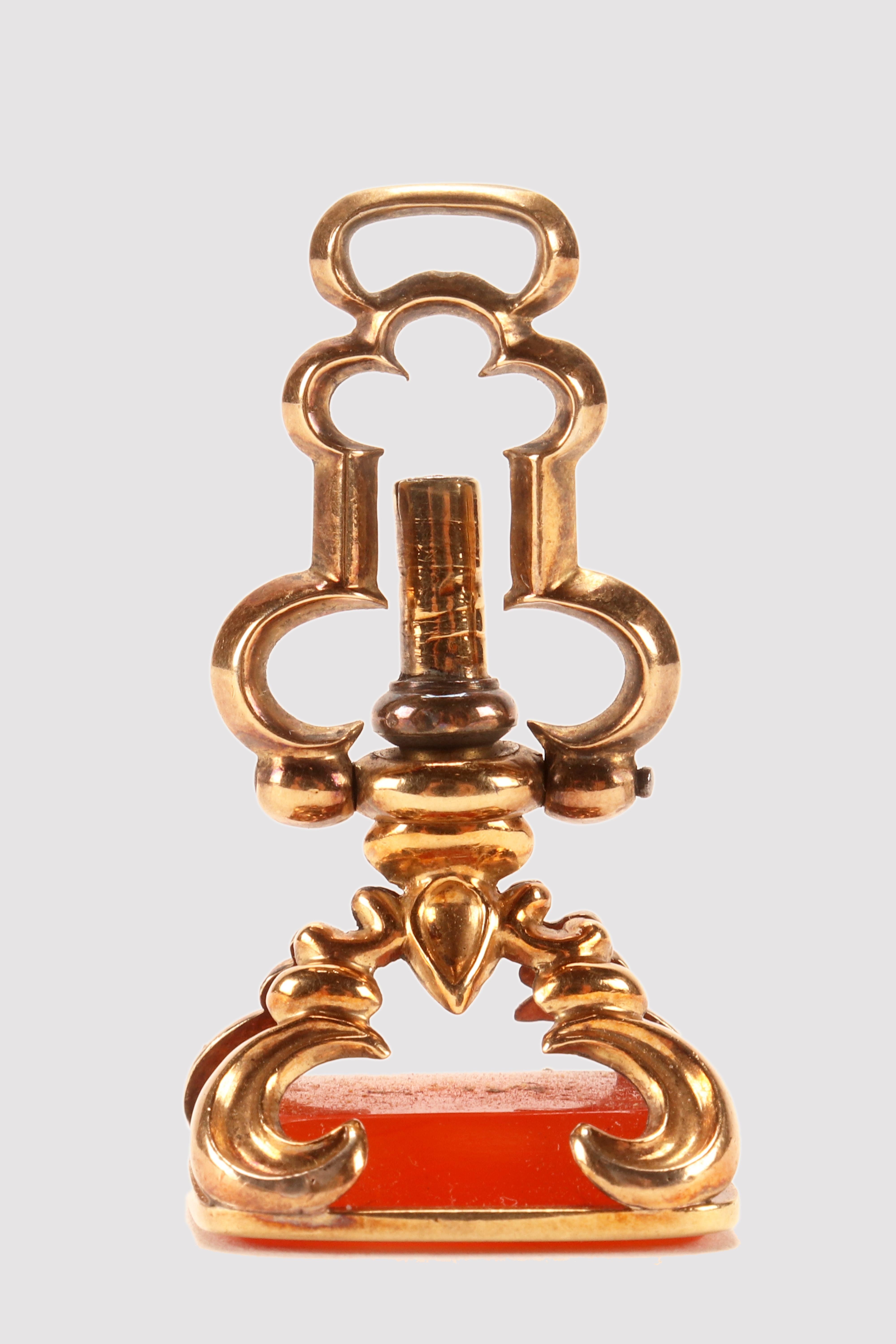 Antique 14 Kt. gold hidden watch key spinning carnelian seal.
The matrix is made out of Cornelian never engraved, and rectangular shaped with beveled edges. A plane gold fascia embraces the cornelian rim and two gold bridge joints at the vertex,