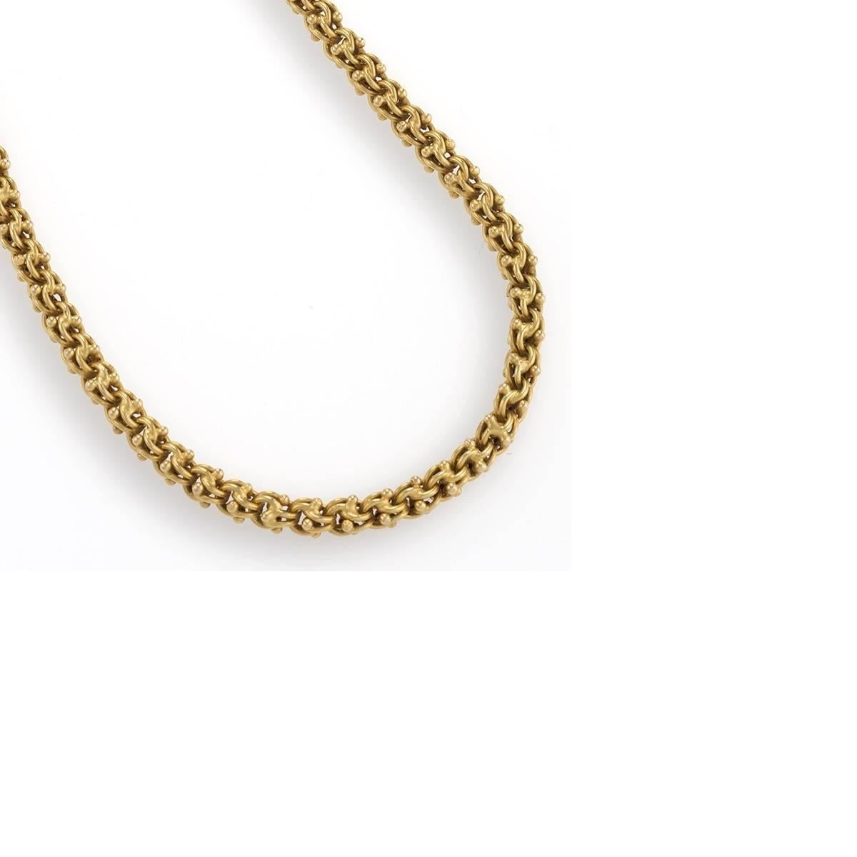This antique gold long chain necklace is composed of tightly interlocking pairs of rounded links edged by small spheres. Generously long and versatile, it can suspend a pendant, or be doubled or tripled to nest on its own or layered with