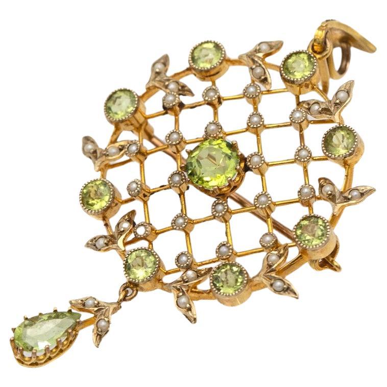 Antique brooch with pendant function preserved in original box (Dykes Brothers Goldsmiths and Jewellers, Glasgow) from the beginning of the 20th century.

Checkered yellow 9K gold setting set with round peridots of approx. 2.50ct total weight and 40