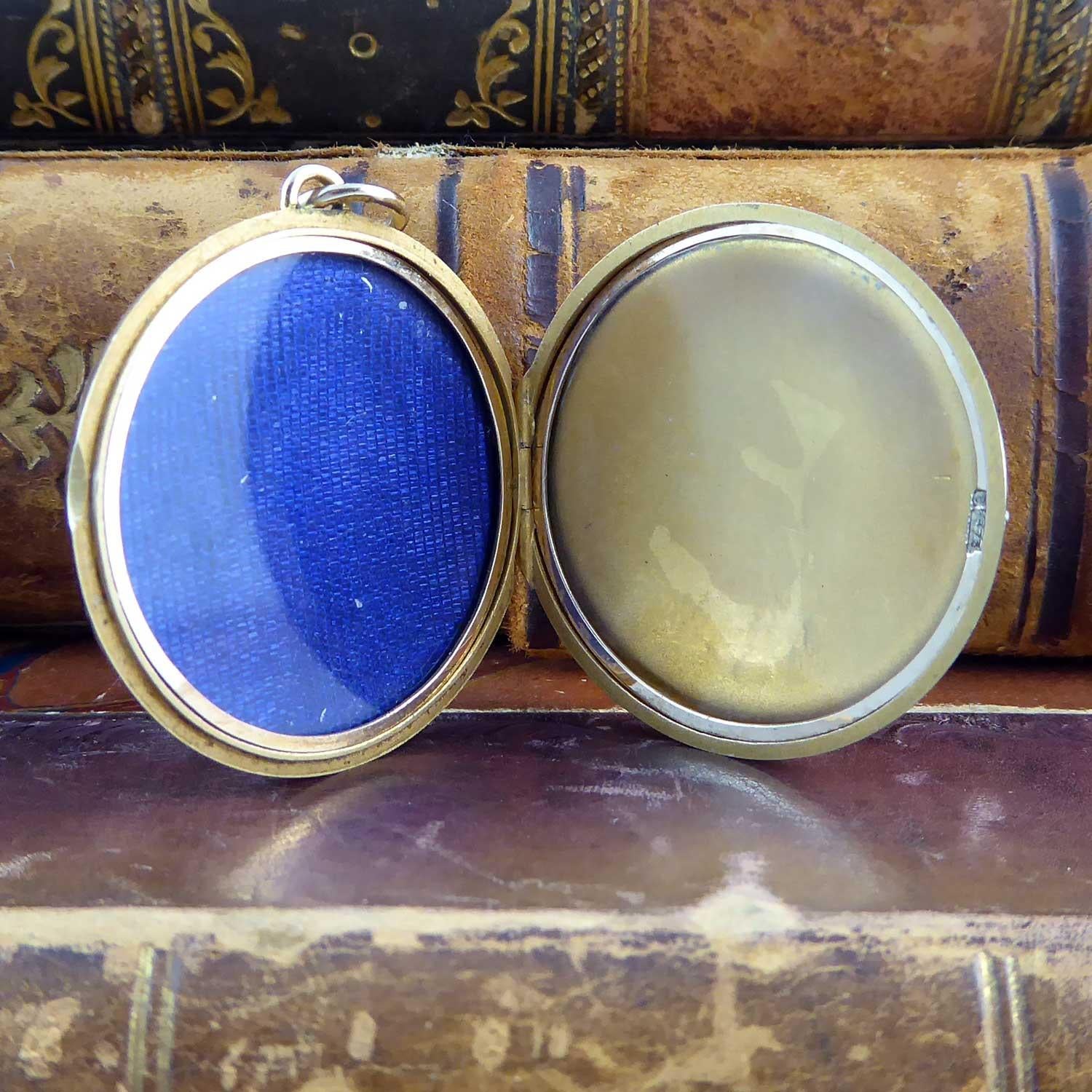 An antique locket created in 9ct gold without any pattern or engraving whatsoever.  The look is plain and simple but nontheless elegant for its restrained design.  Circular in shape with a raised edged border, the locket opens for photographs and