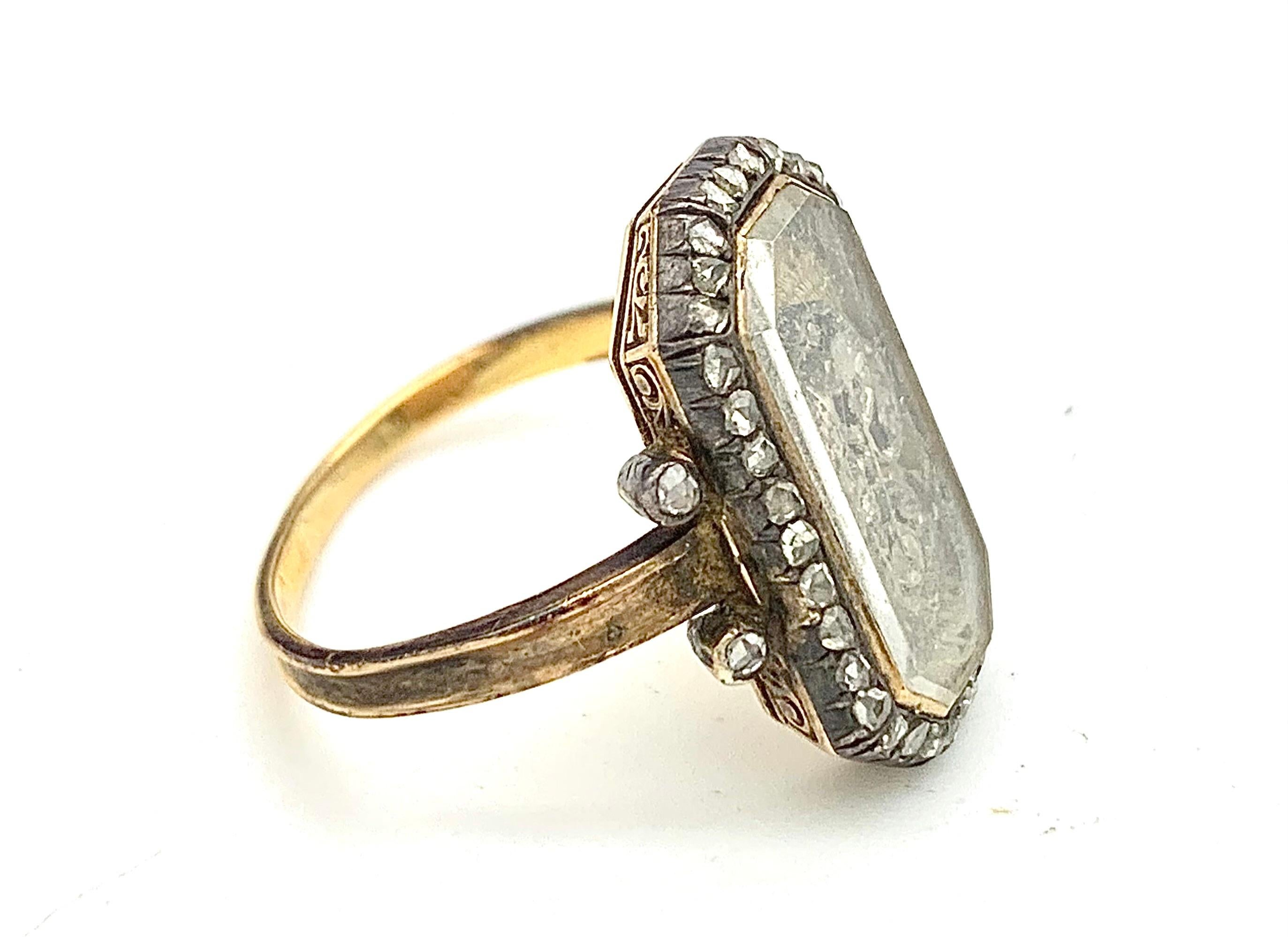 La bague octogonale présente des initiales en argent et serties de diamants roses. Les initiales sont recouvertes de tissu et recouvertes par le verre biseauté d'origine dans une monture octogonale en or. Le monticule d'or est entouré d'une bordure