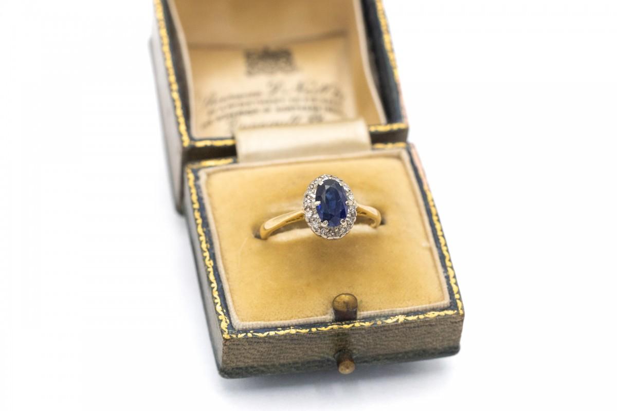 Anello in oro antico con un bellissimo zaffiro ovale e 14 diamanti. Realizzato in oro a 18 carati.
È decorato con uno zaffiro ovale centrale di colore blu intenso e del peso di circa 1,20 ct. Inoltre, quattordici diamanti taglio 8/8 del peso di