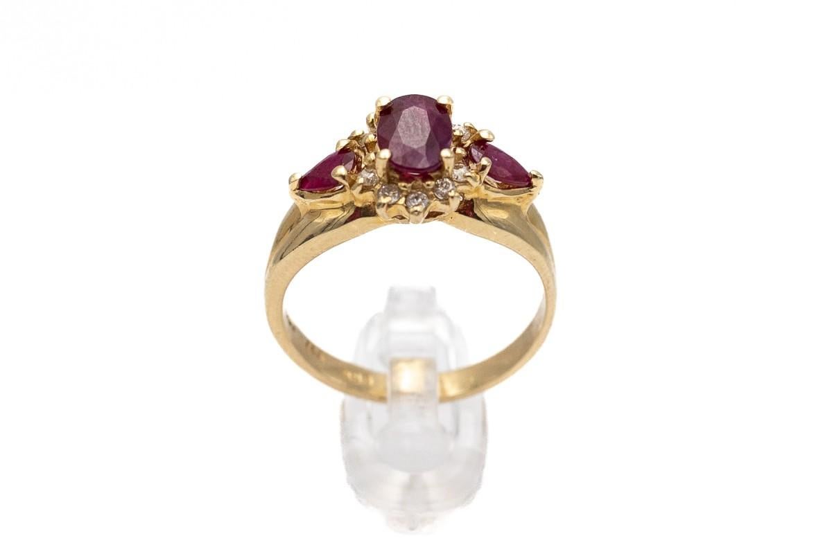 Antique gold ring made of yellow 14-carat gold (0.585 fineness) with a centrally embedded red, oval ruby surrounded by 10 diamonds with a total weight of approx. 0.15 ct

Two additional teardrop-shaped rubies on both sides of the rosette.

Total