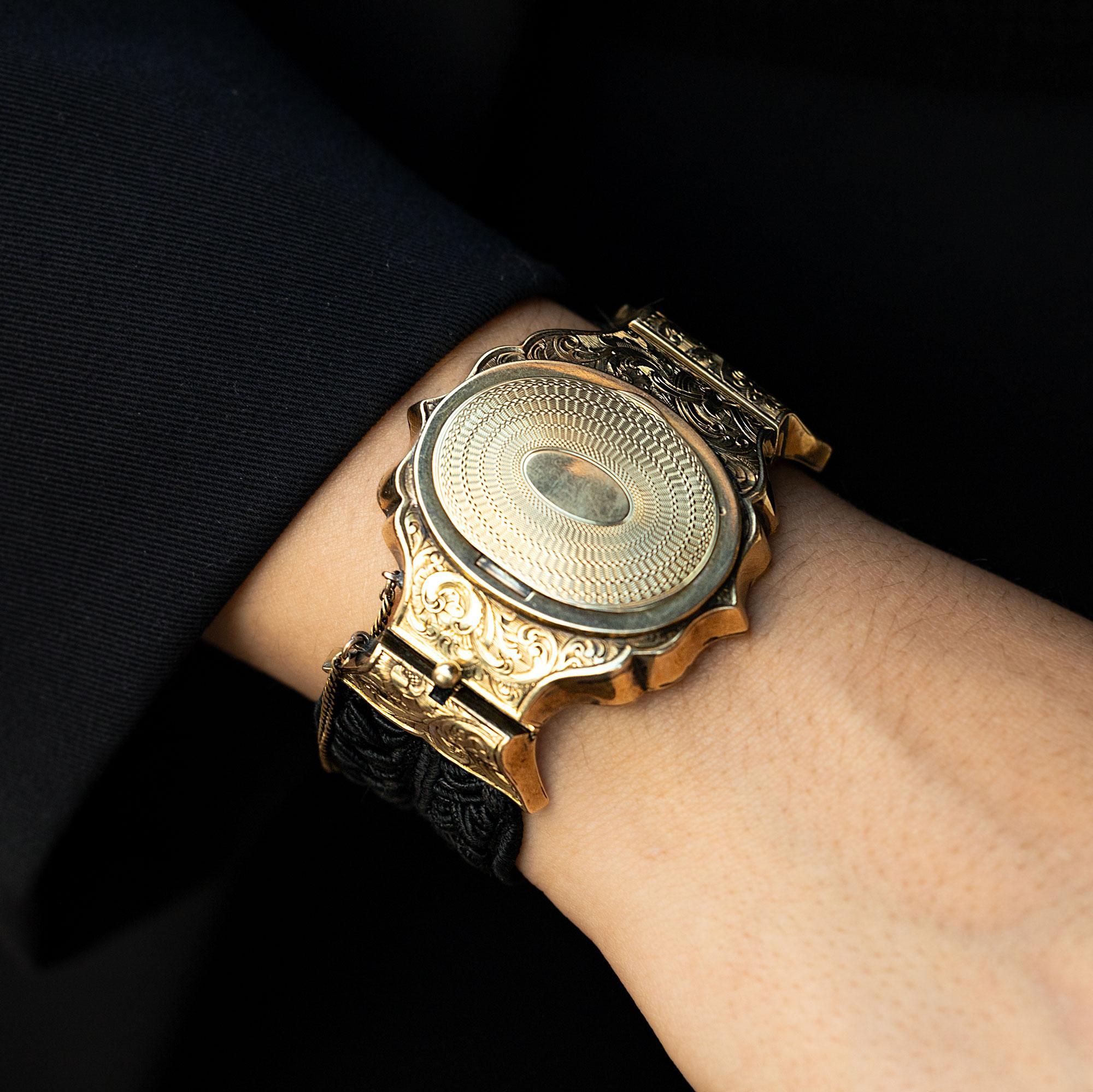 This coveted cuff from mid 19th century is an outstanding example of French Neoclassical design. Also known as Victorian or Napoleon III era, the bracelet face of 14k yellow gold is topped with an elaborate, engine turned cover with scrolling and