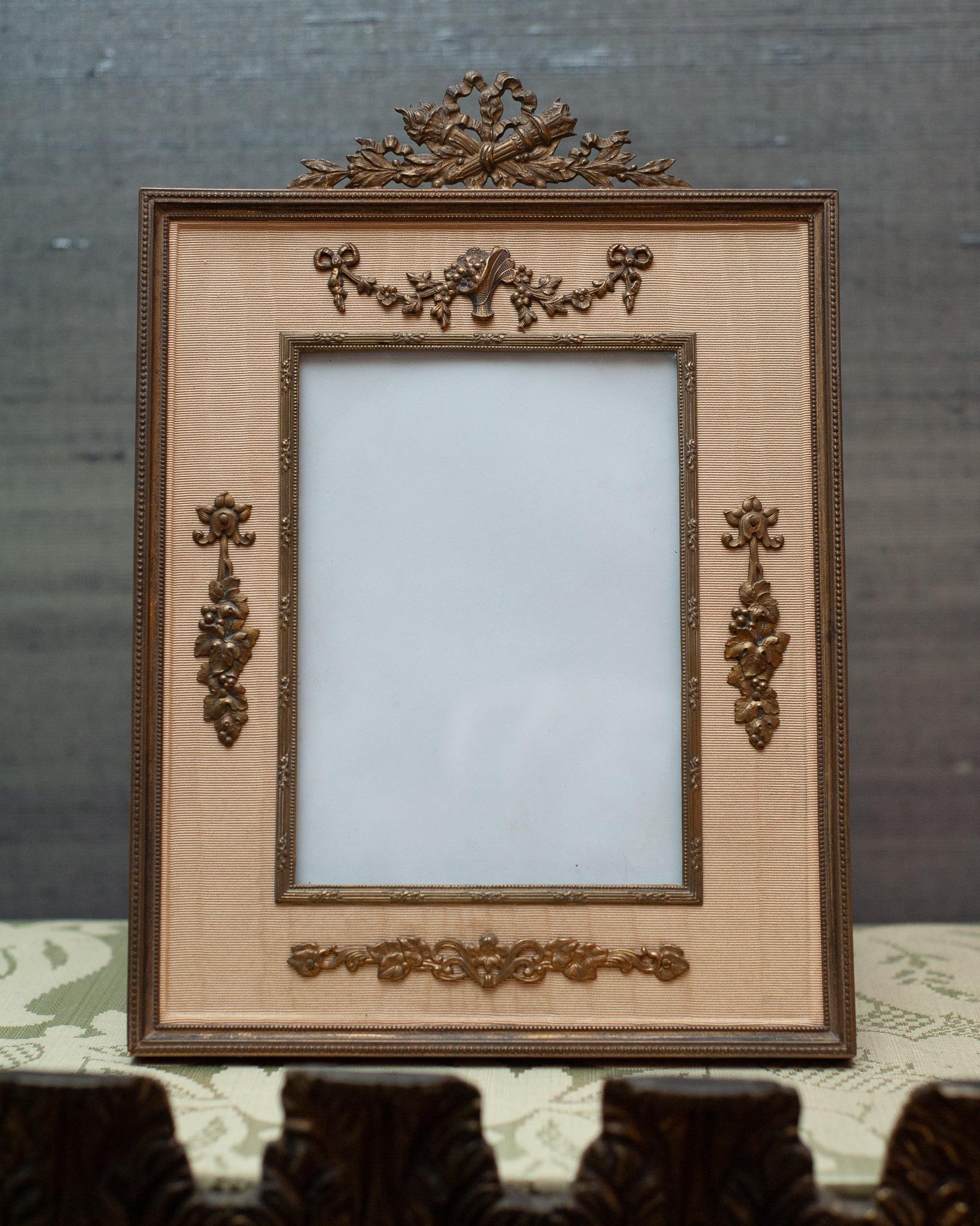 Capture your memories in this French antique bronze picture frame with garlands and gold silk moiré. Accepts one 4
