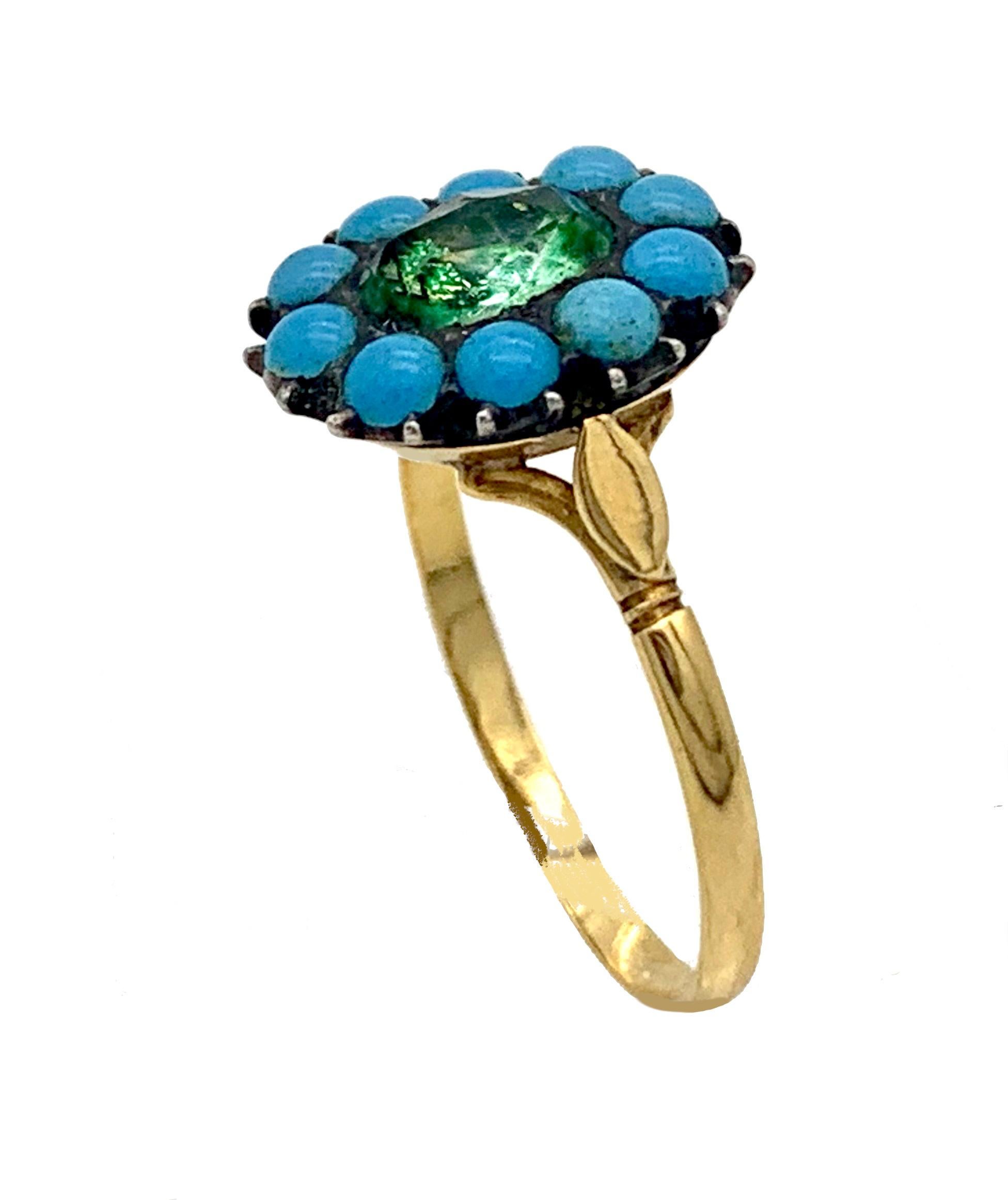 This delicate gold ring was created towards the end of the eighteenth century out of 15 karat gold. The ring head is designed as a flower. In the center we see an oval facetted paste stone that has been mounted over green foil. It is surrounded by