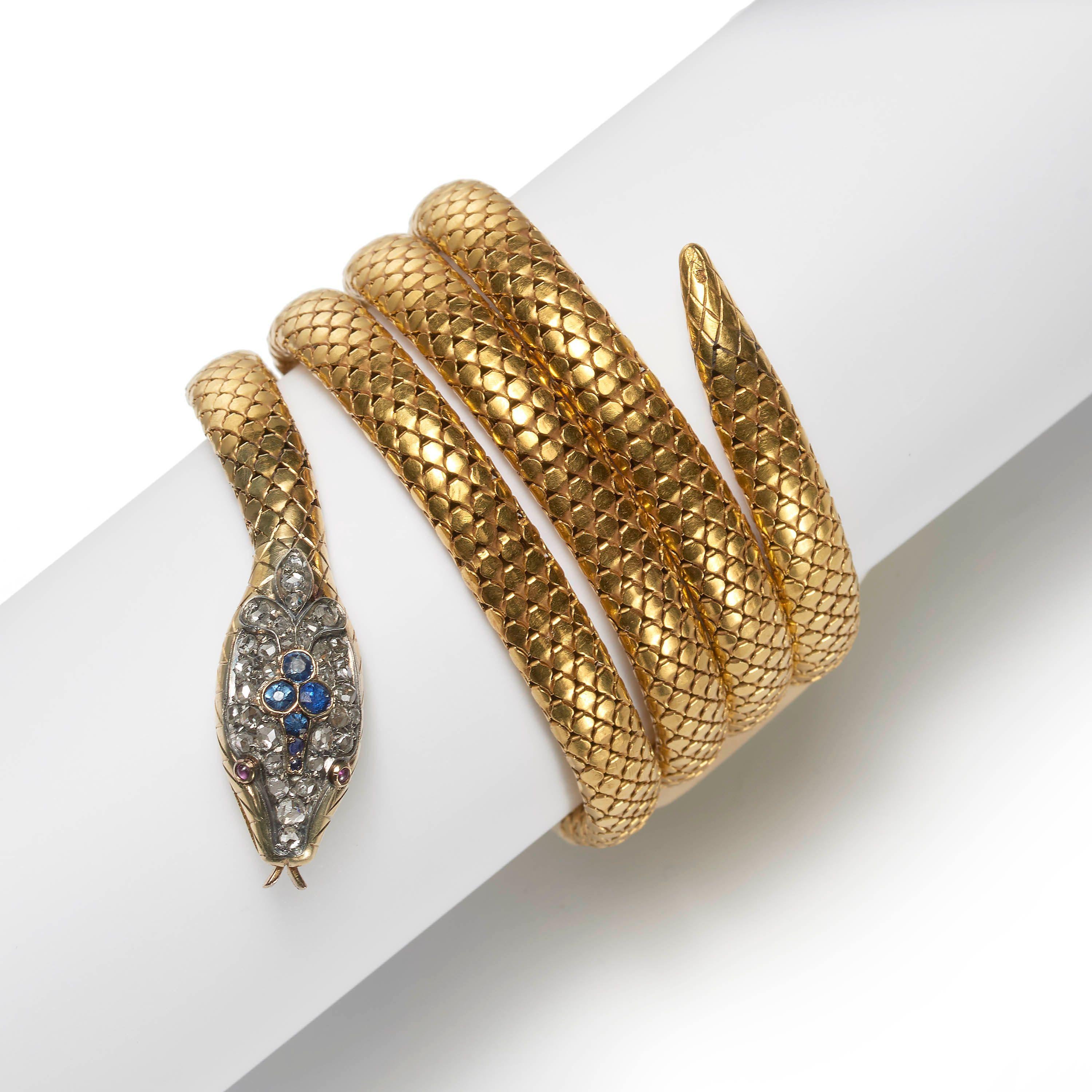An antique gold bracelet modelled as a snake, in the form of four coils of gold flexible links, representing scales. The tail and head are engraved, with faceted sapphires, surrounded by pavé set rose-cut diamonds, set in the head, cabochon-cut ruby