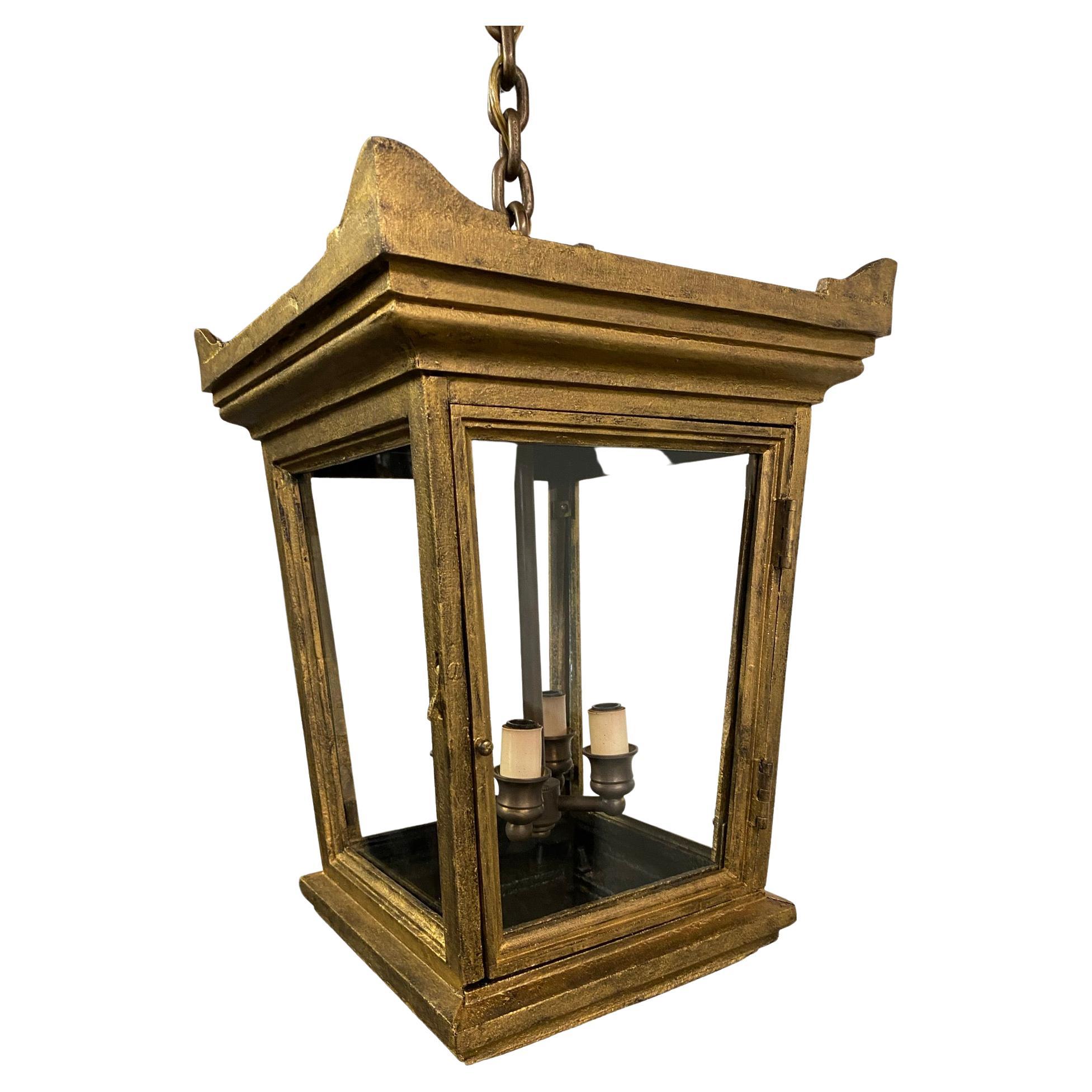 Be it classical, Neoclassical or Regency style, this gold toned hanging lantern will add a touch of classic influence to your entryway hall interior or exterior. Crafted in iron this lantern has a hint of Chinese pagoda lantern influence giving it a