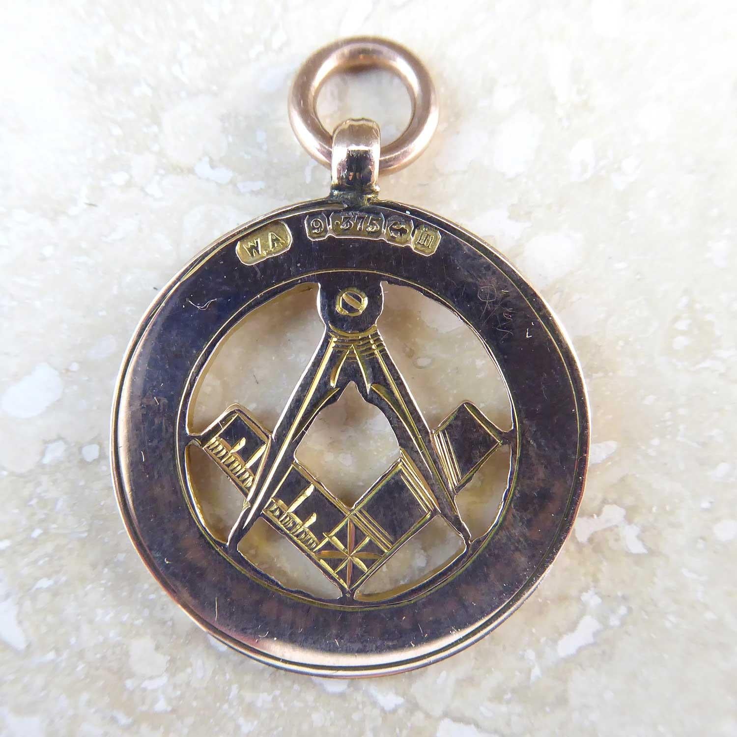 An antique gold watch chain fob dating from 1911.  The centre of the fob depicts the Freemason signs of the square and compass set within an outer border 1/8th of an inch wide and handsomly engraved with an acanthus leaf design.  The reverse of the