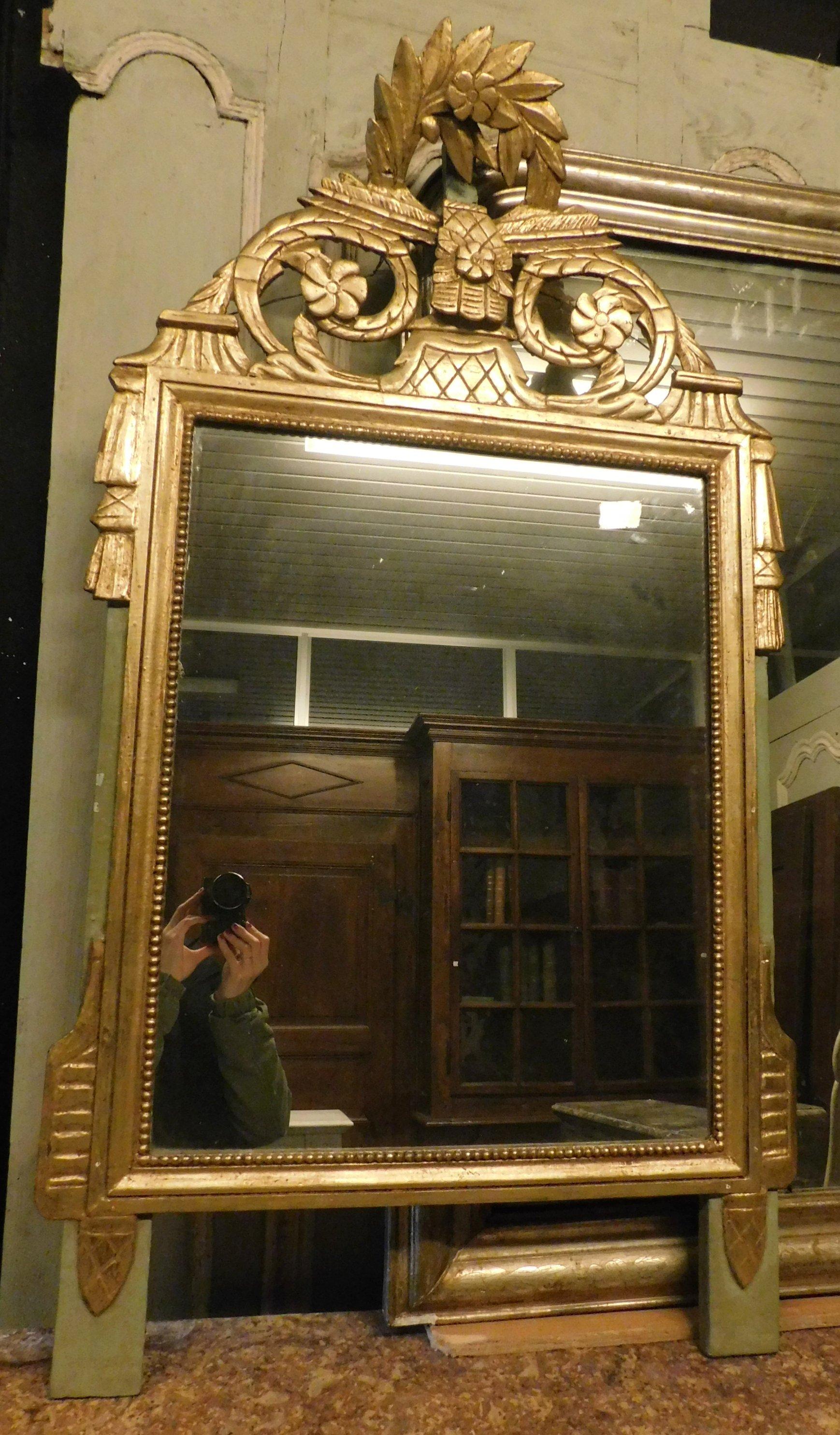 Ancient golden mirror with floral decorations
and foliar, built by Italian artisans in the 19th century, leaf gilding and green lacquered legs, excellent to be placed above a fireplace or in a luxurious room to which to give an original and chic