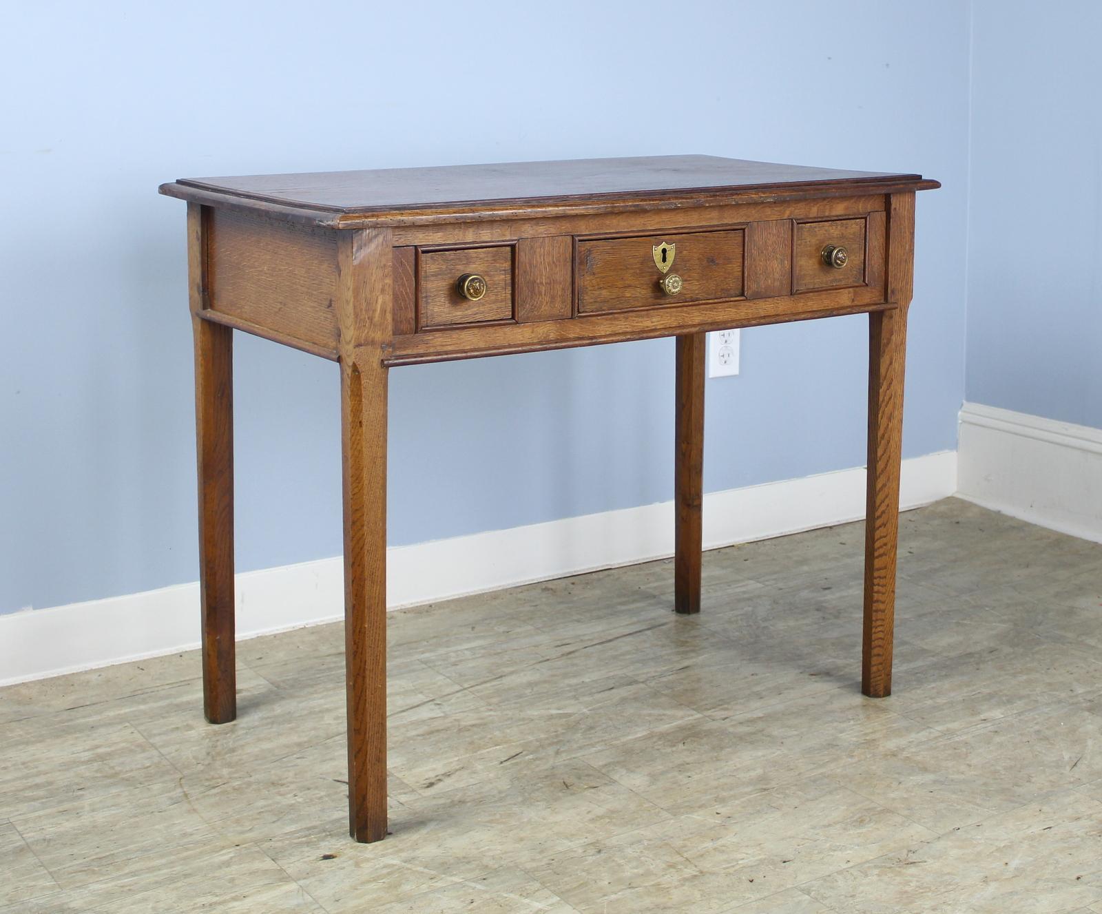 An eye catching side table in English golden oak. The three roomy drawers are accented with original cockbeading. The top is substantial and rounded at the sides for additional style. Good grain and patina.
