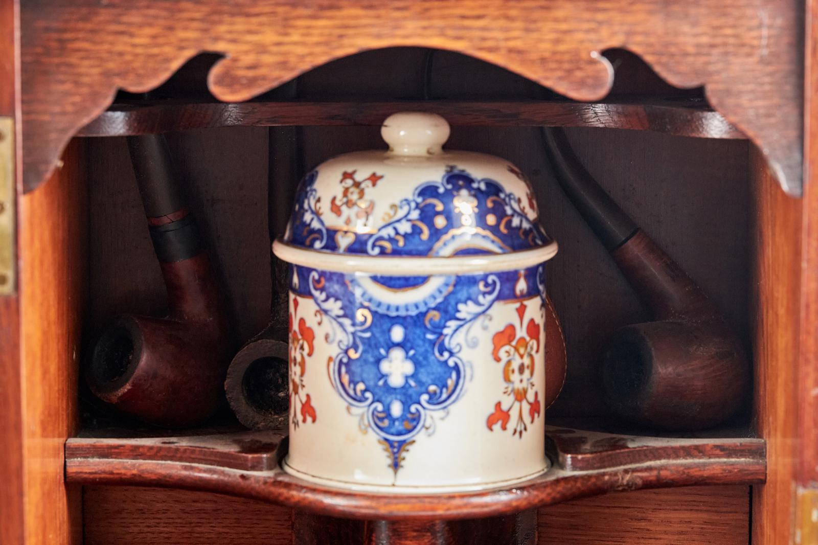Antico armadietto per fumatori in quercia dorata con un'anta singola vetrata che si apre per rivelare un interno attrezzato con 2 cassetti corti e un cassetto lungo, tutti con maniglie ornate originali. Colore e condizioni incantevoli.