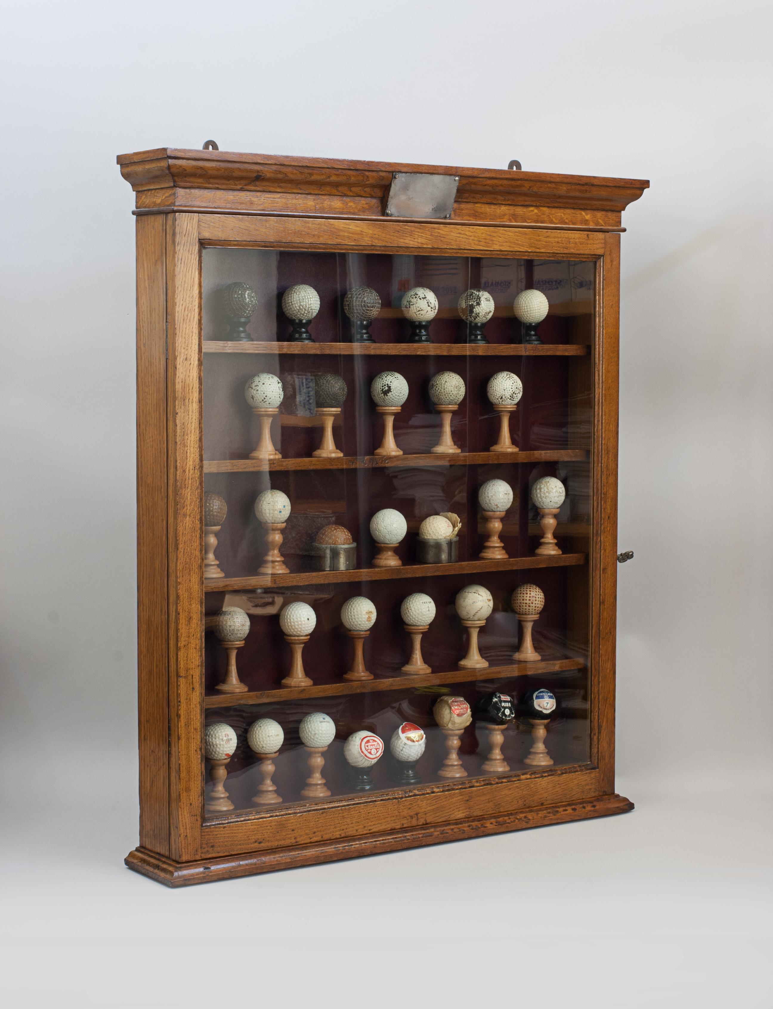 Antiguo expositor de bolas de golf de roble.
Vitrina de pared victoriana con una colección de 32 pelotas de golf vintage originales. El armario tiene una sola puerta acristalada con cerradura y un fondo de imitación de cuero rojo. Treinta bolas