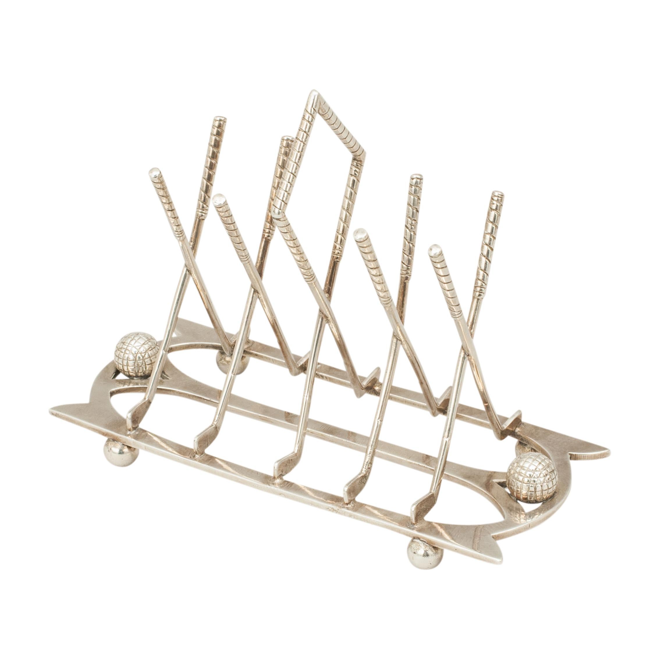 Antique golf toast rack.
A silver plated four division toast rack with crossed golf clubs, mounted on a shaped base, raised on tiny bun feet. There is a small gutty pattern golf ball on both ends of the toast rack. Would also work well as a letter