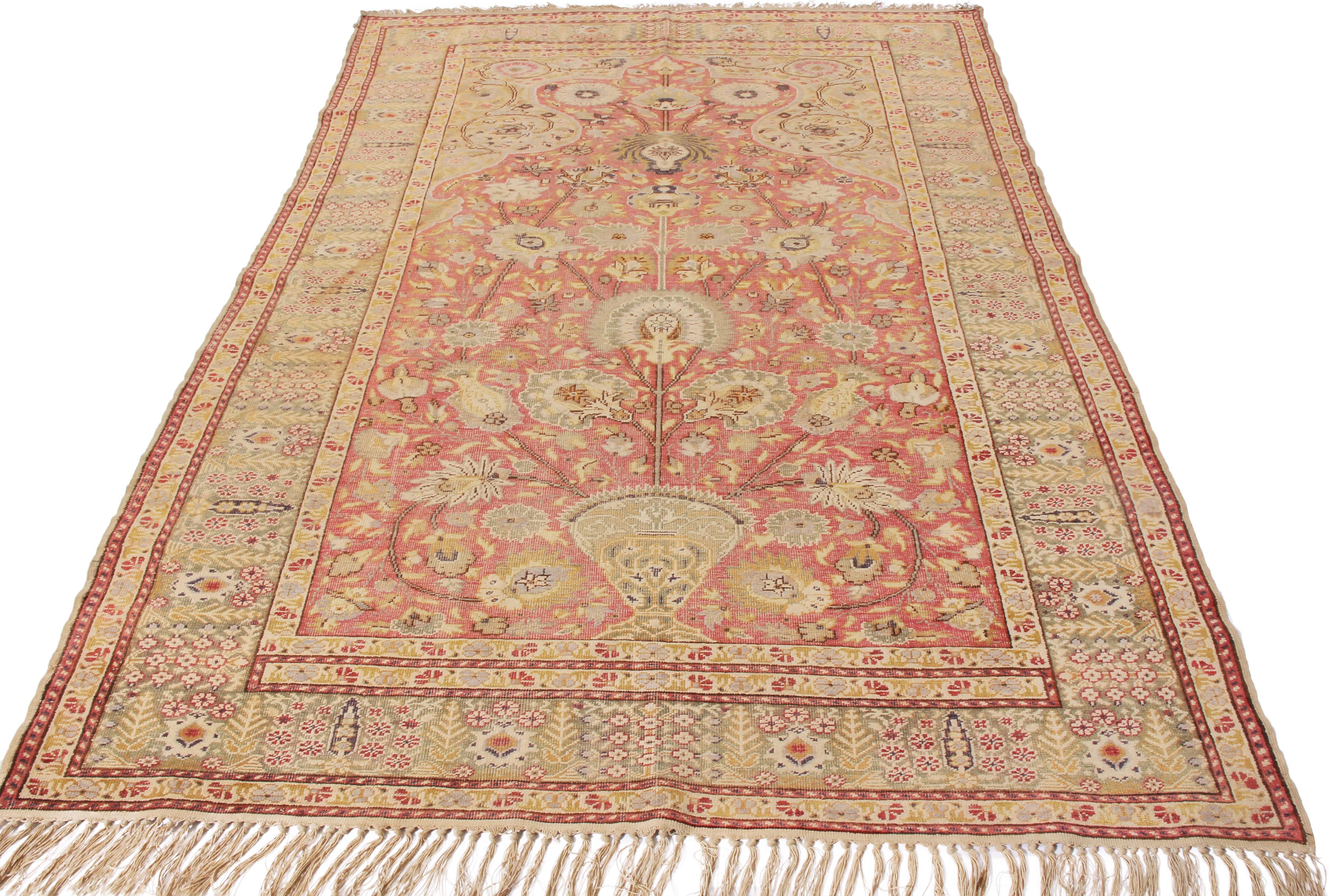 Originating from Turkey in 1890, this hand knotted antique Gordes wool rug marries uncommon tea green and pink colorways with a unique employment of the traditional tree of life motif. Surrounding a finely woven curvilinear field design with sole